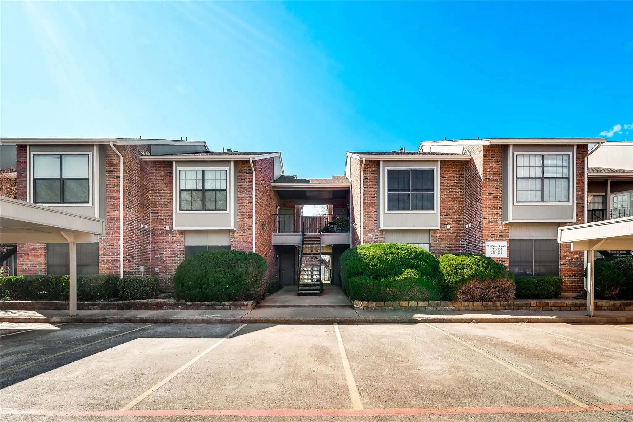 Brick and siding exterior with multiple windows and covered parking structures