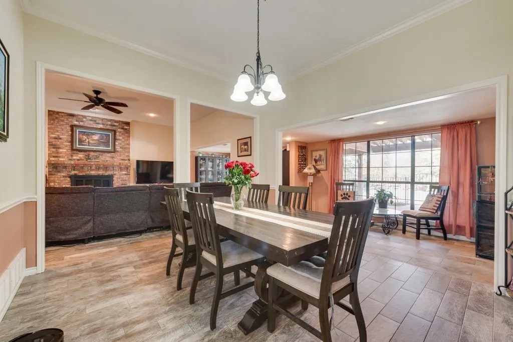 Spacious dining area with wood-finish flooring, crown molding, and a multi-light chandelier