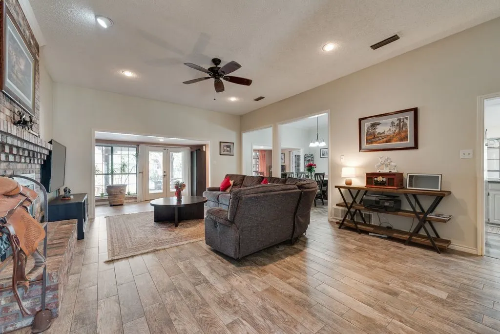 Spacious living area featuring wood-finish flooring, a brick fireplace, recessed lighting, and a ceiling fan