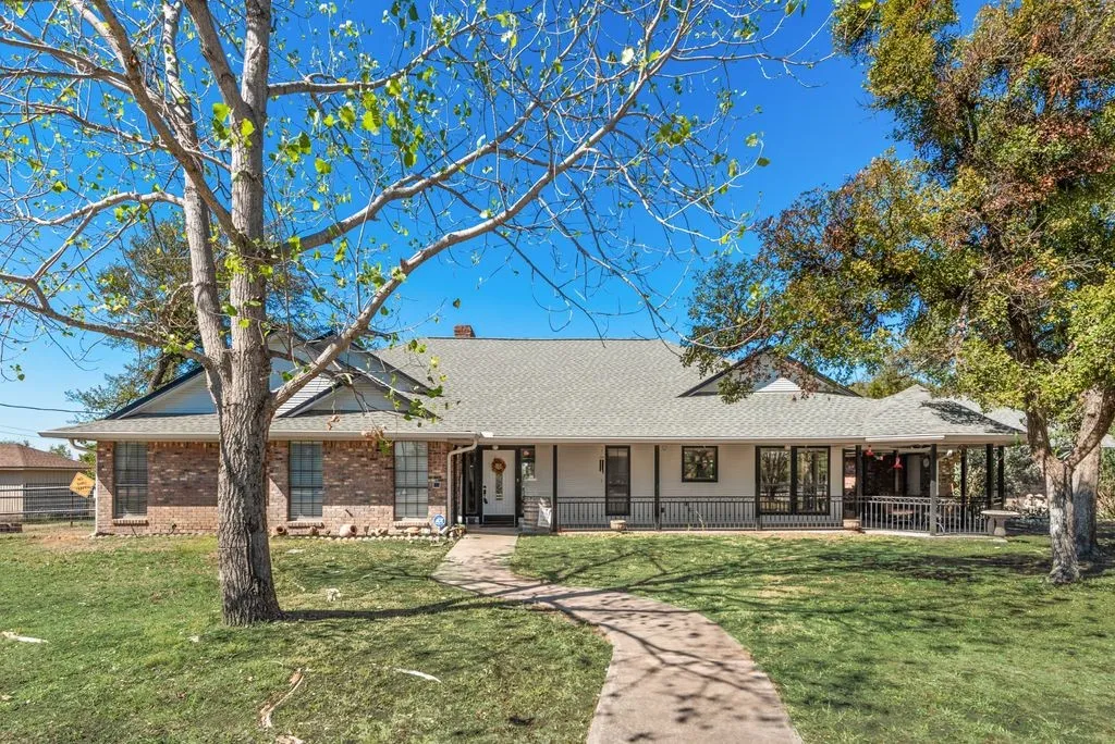 Brick and siding exterior with a covered front porch, a covered side patio, and a winding concrete pathway