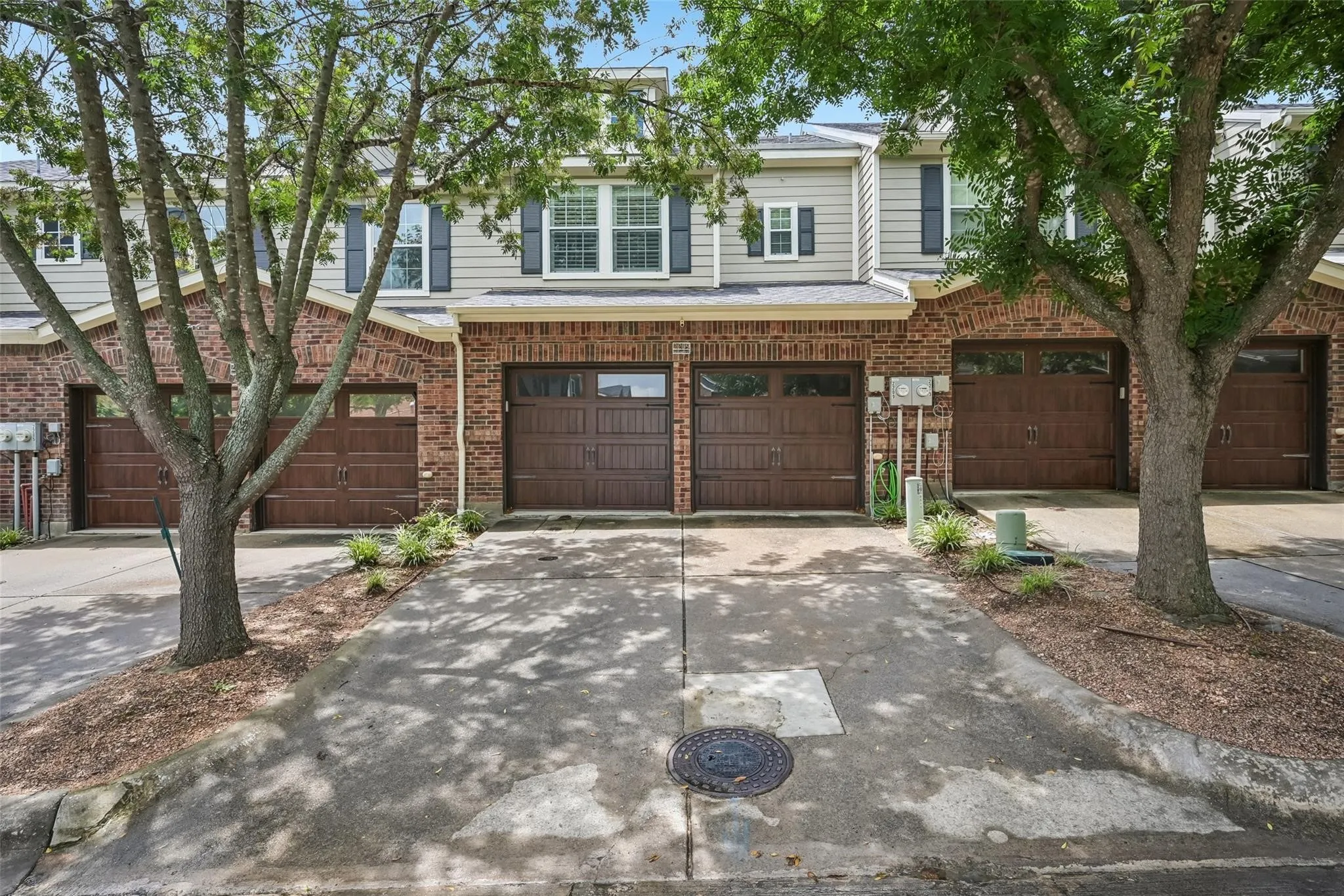 Brick and siding exterior with dark wood-finish garage doors