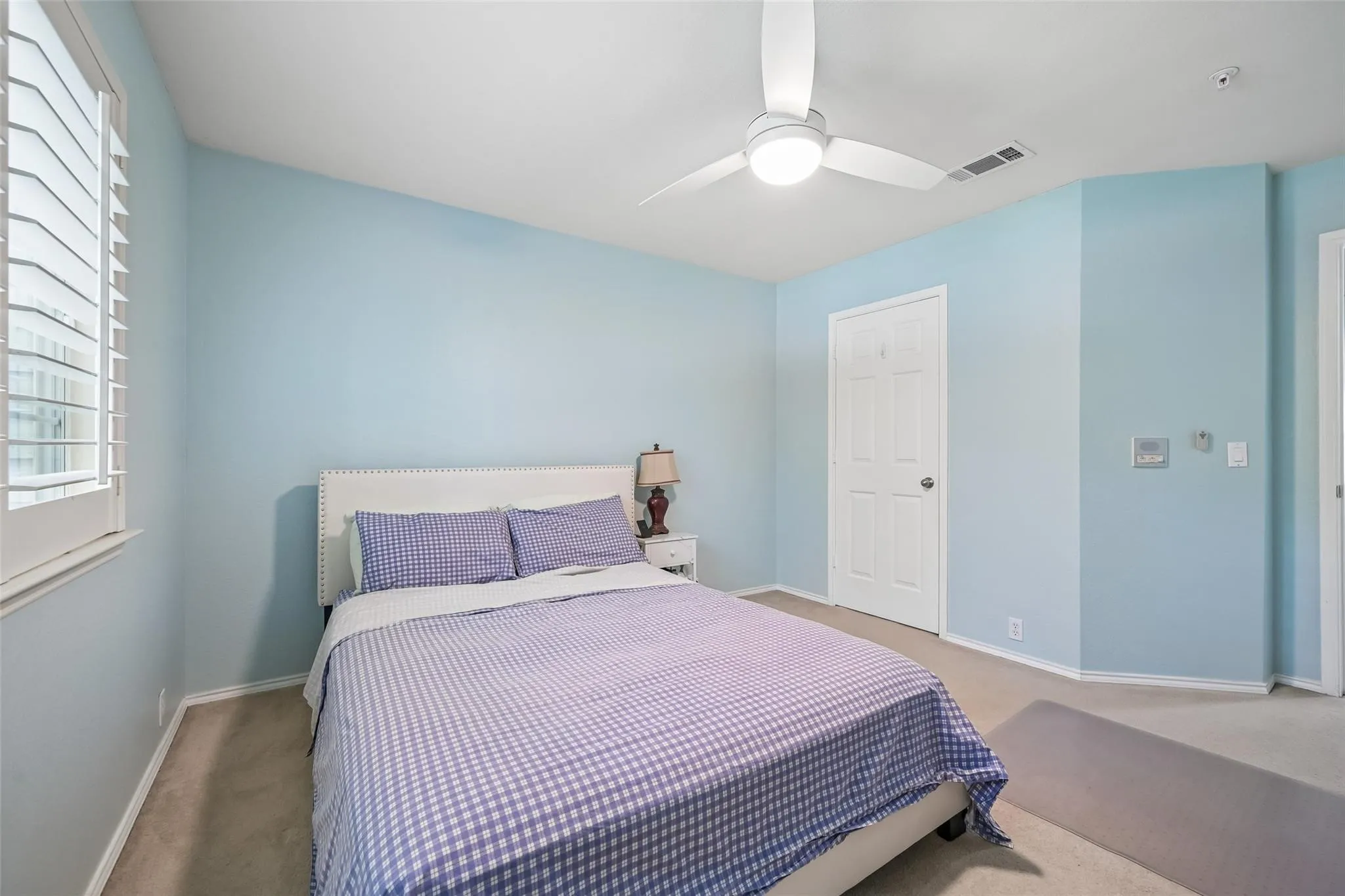 White plantation shutters, ceiling fan with integrated lighting, wall-to-wall carpeting, and a paneled interior door