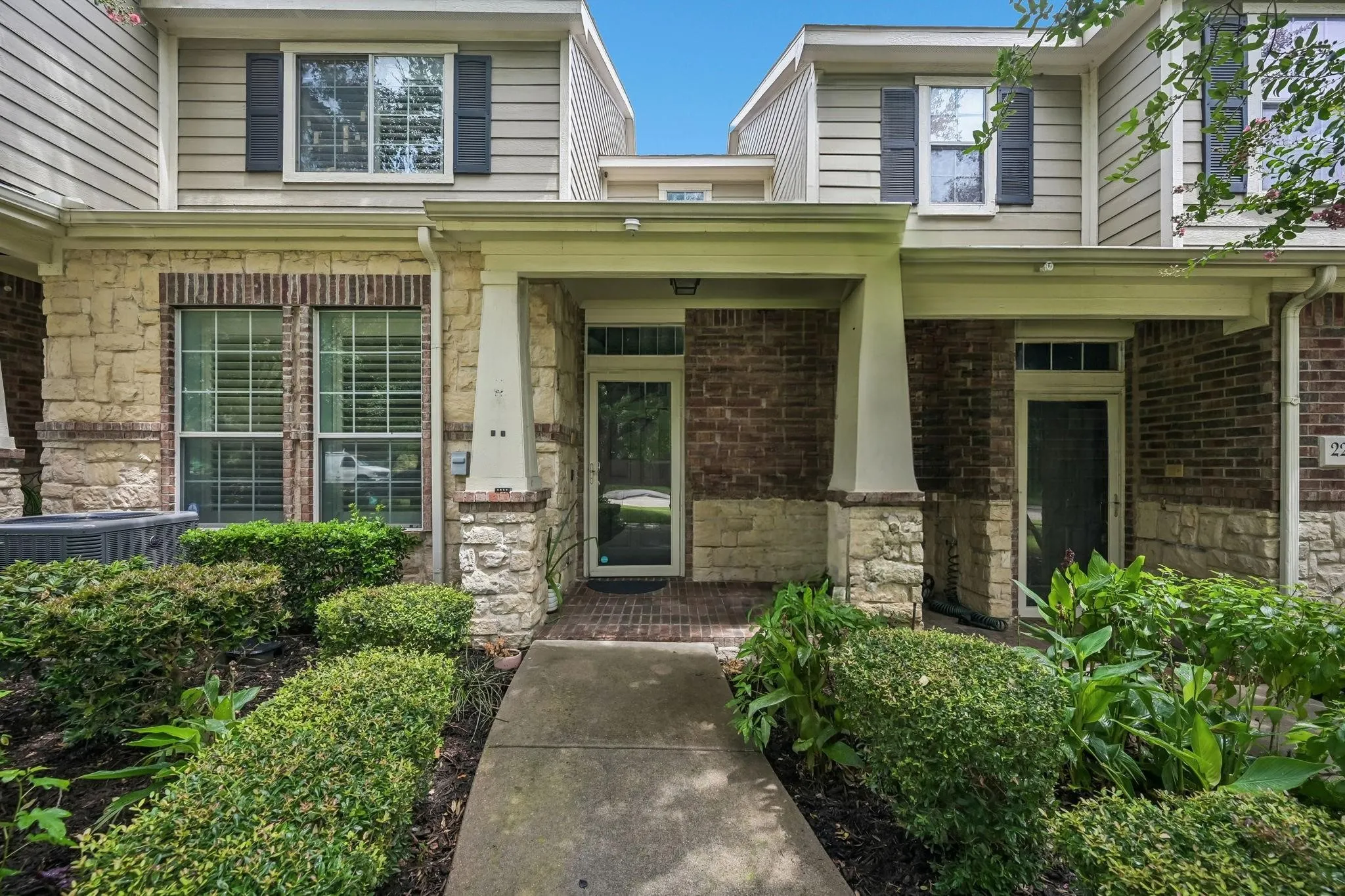 Multi-level facade with brick and stone accents, covered entry, and manicured landscaping