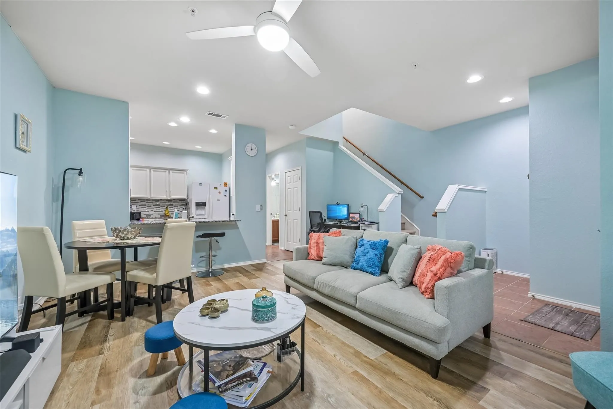 Wood-finish flooring, recessed ceiling lighting, ceiling fan, and a kitchen pass-through with a built-in breakfast bar