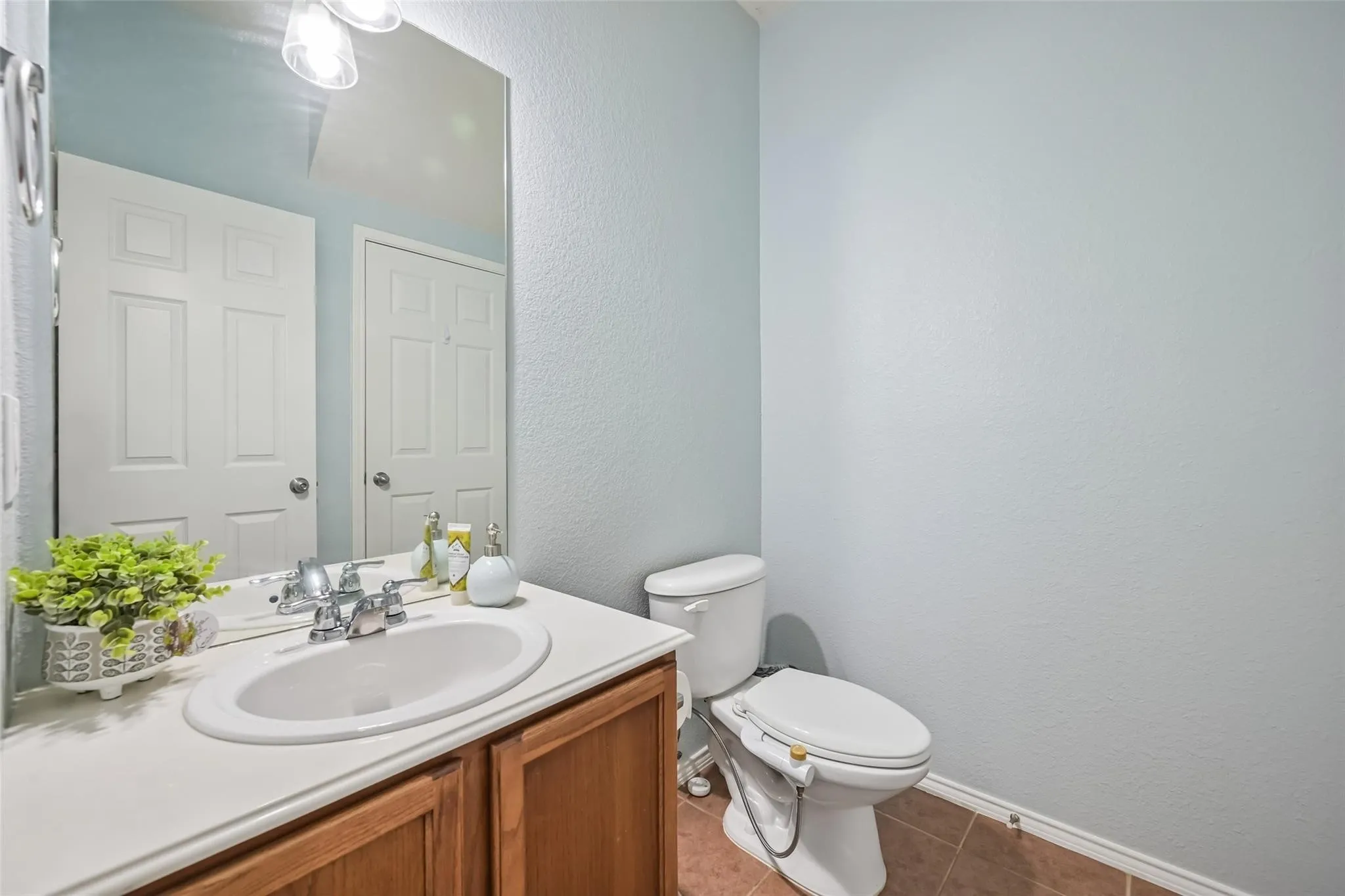Bathroom featuring a vanity with an integrated sink, chrome-finish faucet, and a large wall-mounted mirror