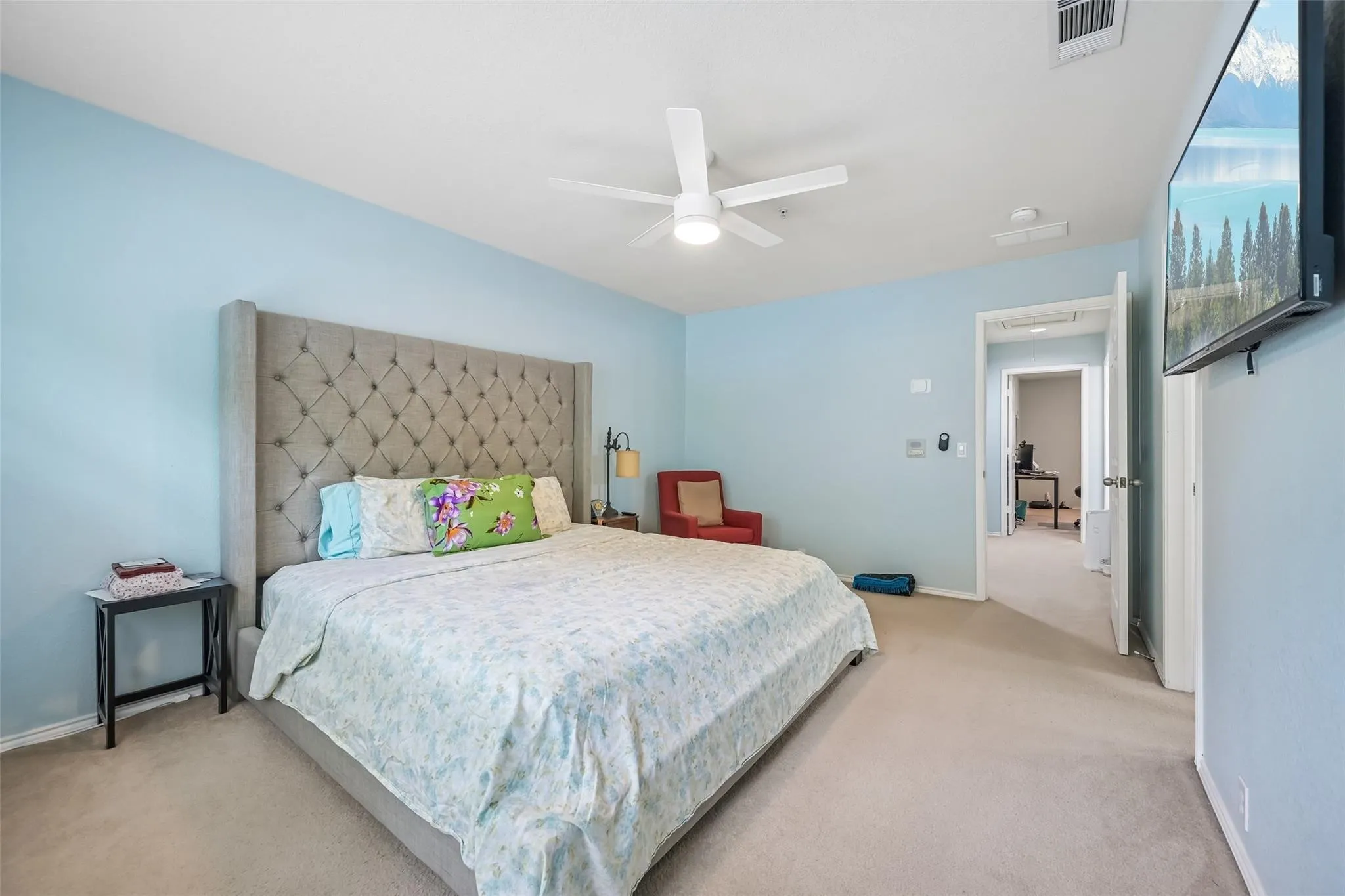 Carpeted bedroom featuring a ceiling fan with integrated lighting and a doorway leading to an additional interior room