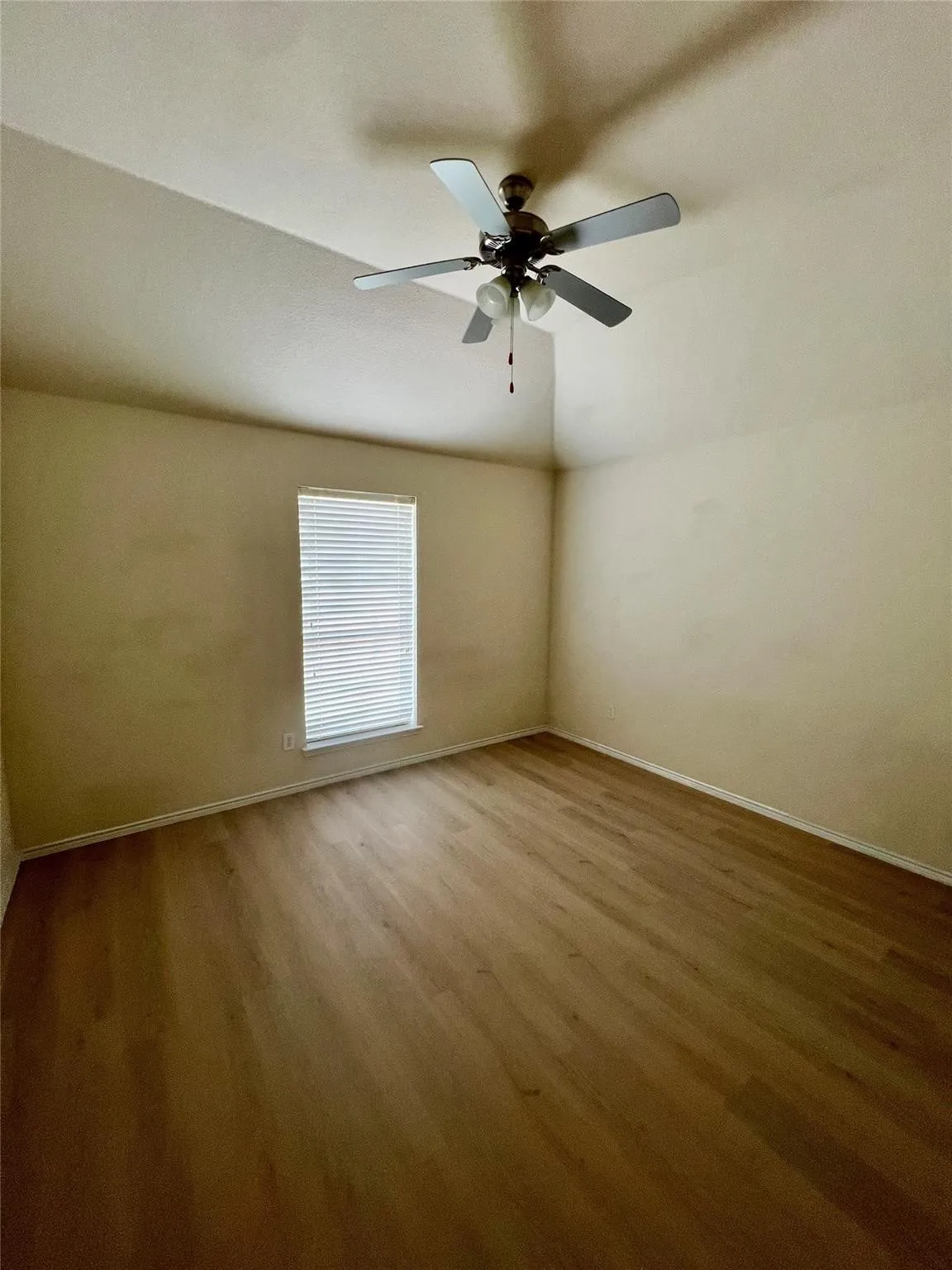 Vaulted ceiling with a ceiling fan, wood-finish flooring, and a window with blinds