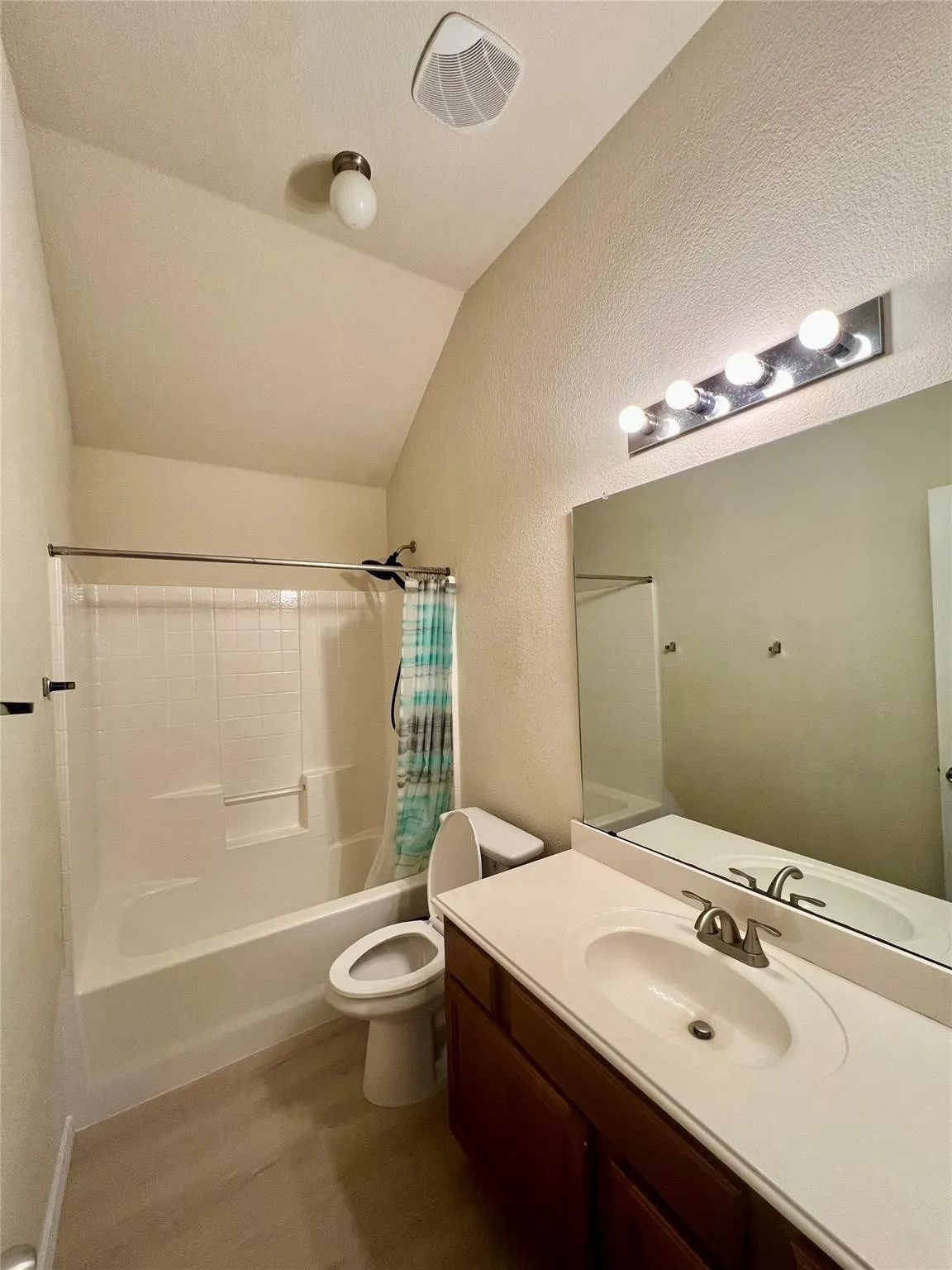 Bathroom featuring a white bathtub, toilet, and vanity with a single basin sink