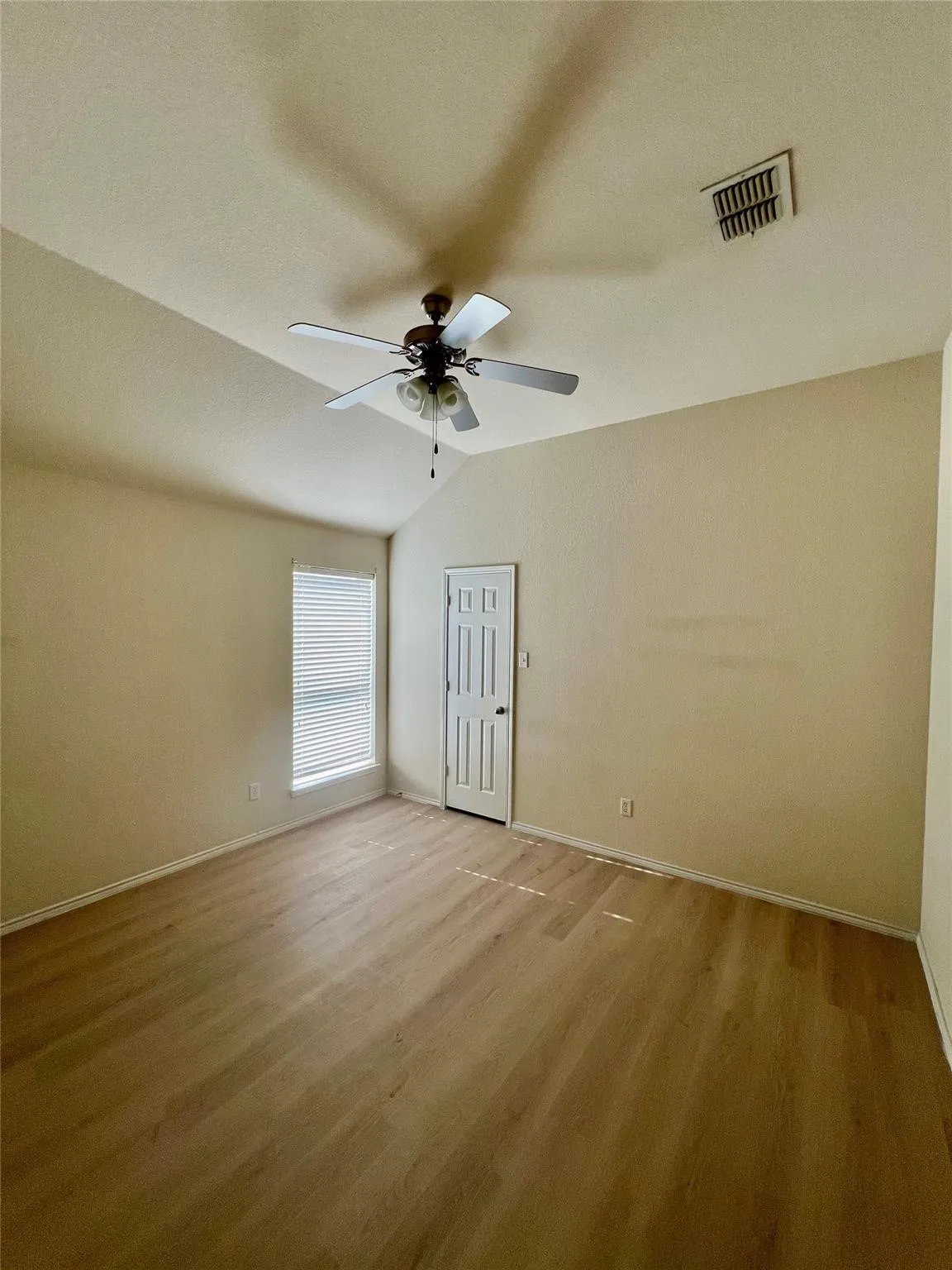 Room with wood-finish flooring, a vaulted ceiling, a ceiling fan, and a window with blinds