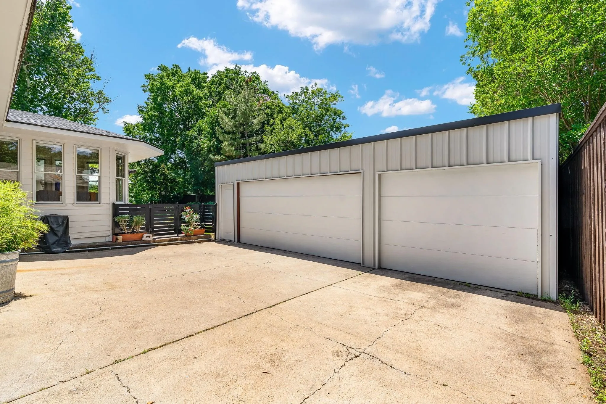Six-car garage with white paneled doors, concrete driveway, and a privacy fence