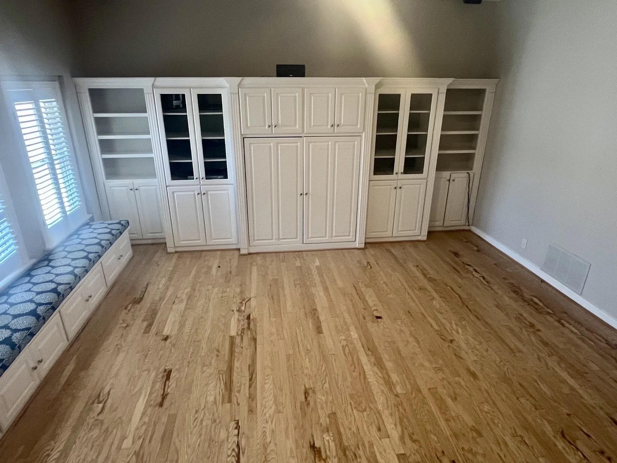 Hardwood flooring throughout, custom built-in cabinetry with glass-front display, integrated storage, and window seating with storage