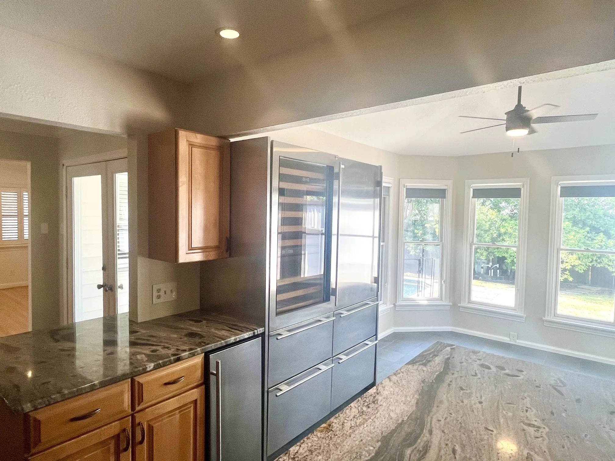Stainless steel appliances, built-in wine refrigeration, wood cabinetry, stone countertops, and a ceiling fan