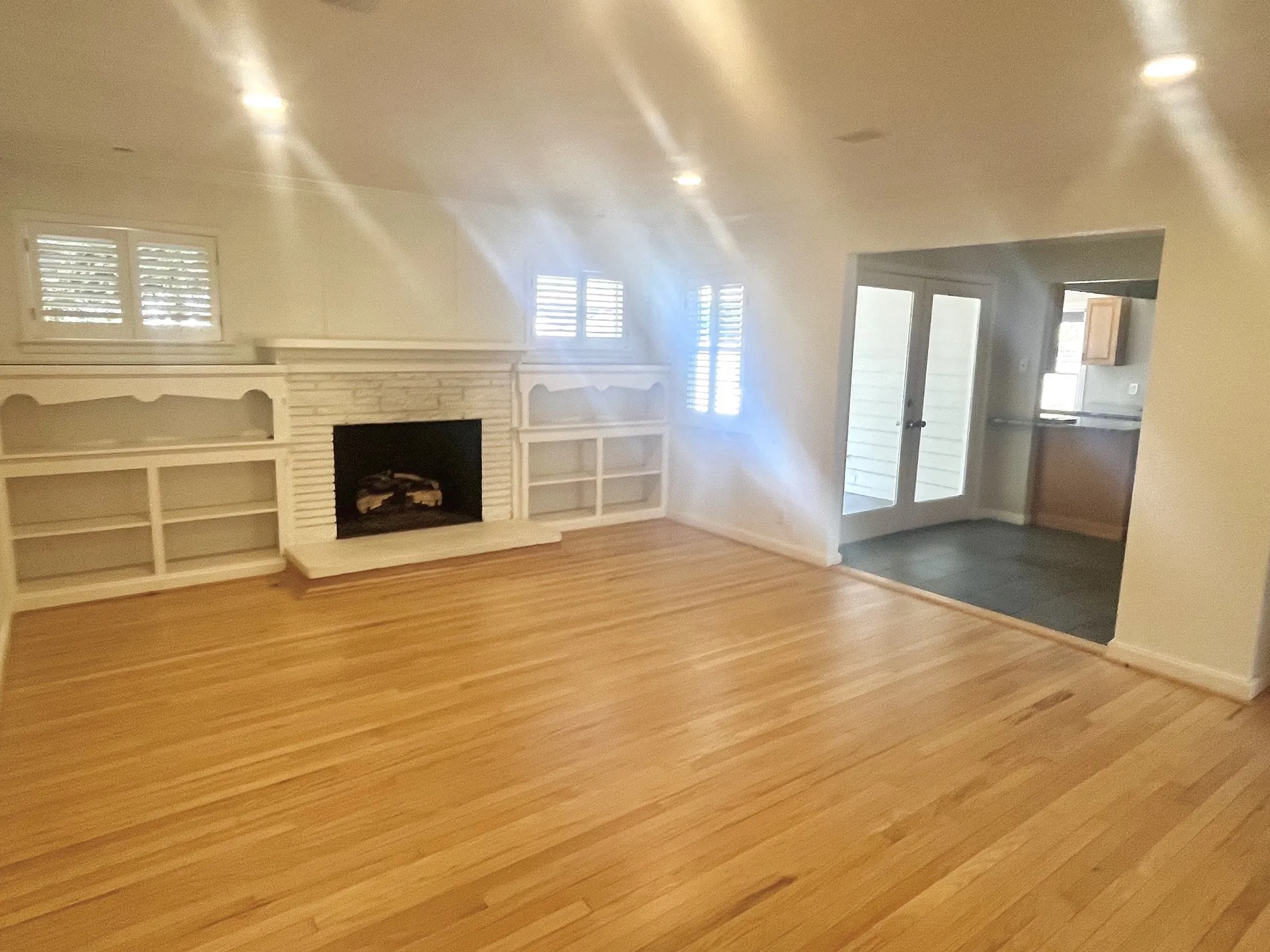 Hardwood flooring, recessed lighting, built-in shelving, stone-clad fireplace, and plantation shutters