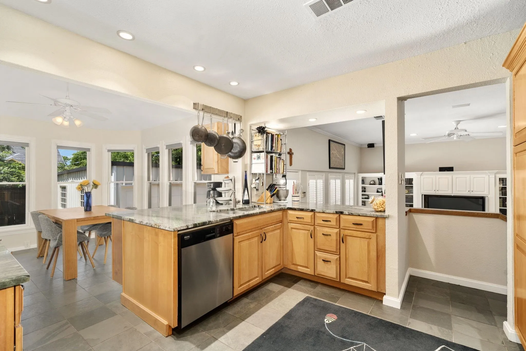 Kitchen featuring wood-finish cabinetry, stainless steel appliances, stone countertops, recessed lighting, and tile flooring