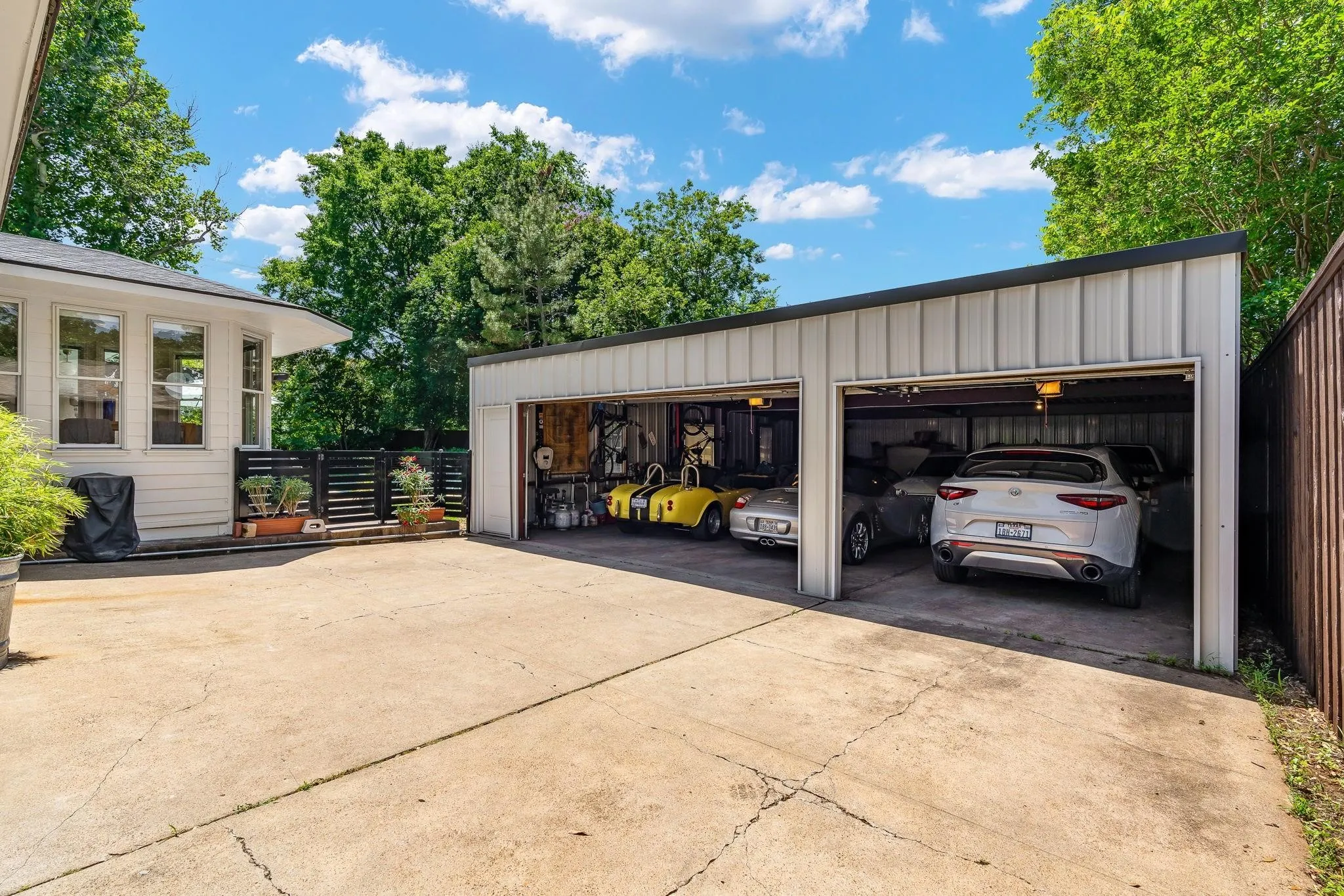 Detached multi-bay garage with electric car charger, a flat black roof, and concrete floor