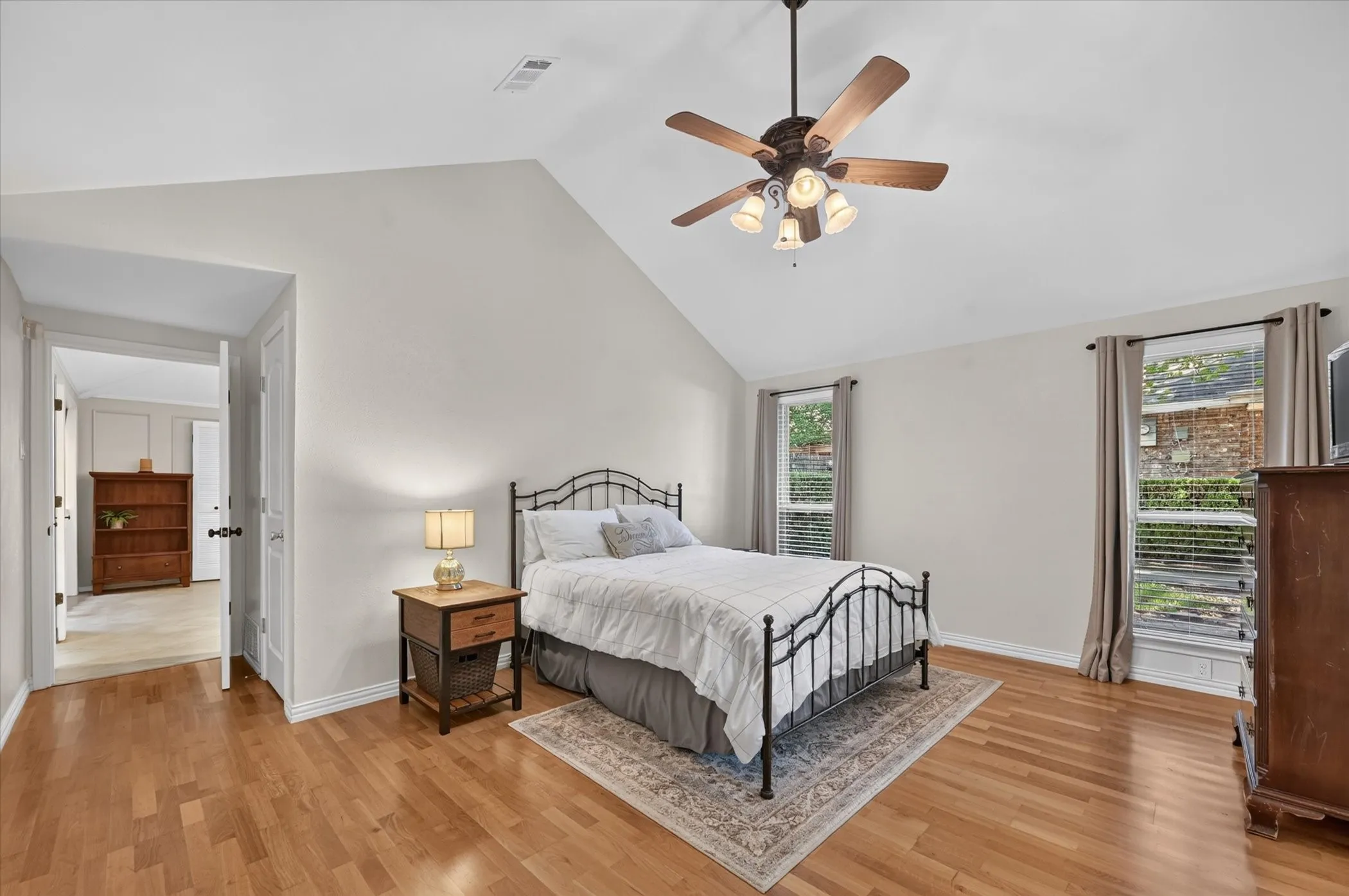 The spacious downstairs primary bedroom has a vaulted ceiling, ceiling fan,hardwood floors & windows for natural lighting.