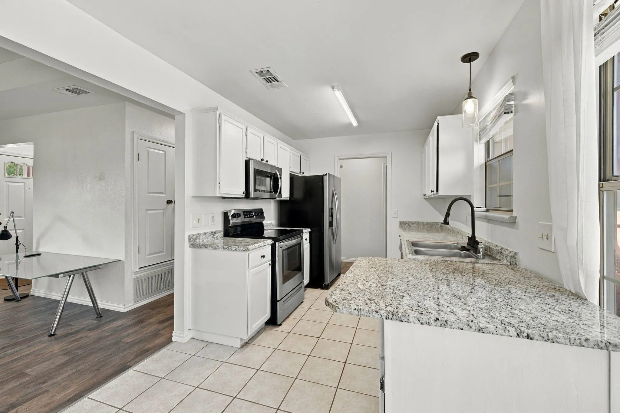 Kitchen featuring white cabinetry, light-colored countertops, stainless steel appliances, and tile flooring