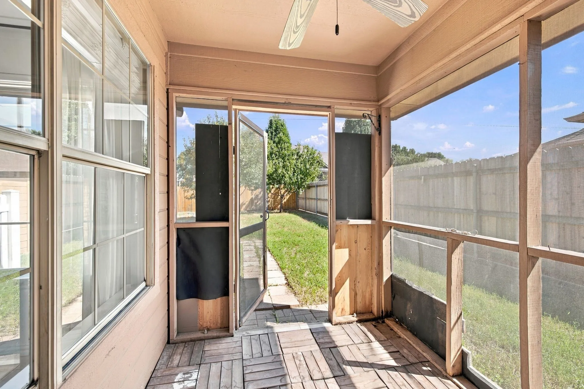 Screened porch featuring a ceiling fan, plank-style flooring, and direct access to a fenced yard