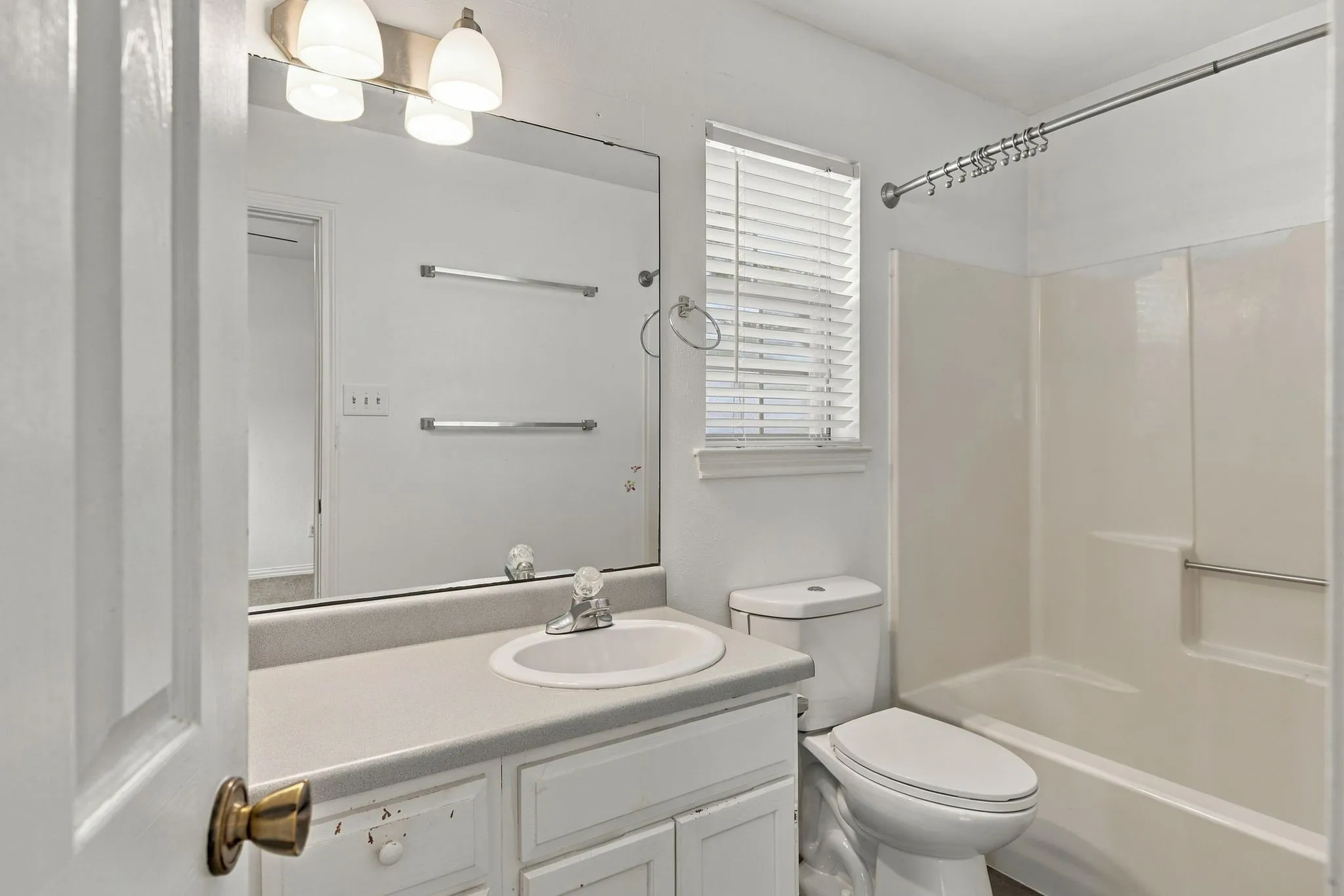 White vanity with integrated sink, rectangular mirror, and an overhead light fixture