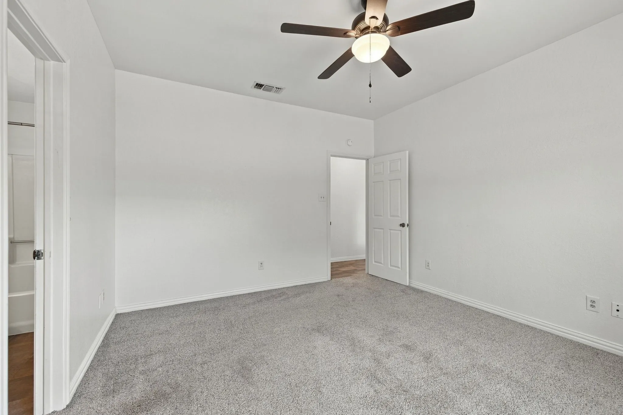 Neutral wall paint, ceiling fan with integrated lighting, gray carpet flooring, white trim, and a paneled interior door