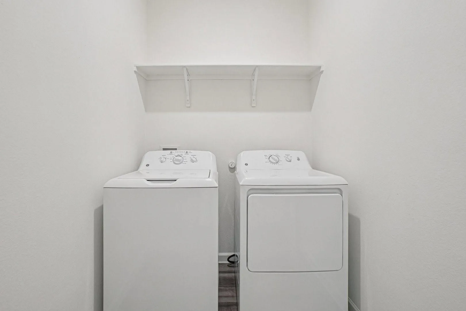White top-load washing machine and front-load dryer with an overhead shelf