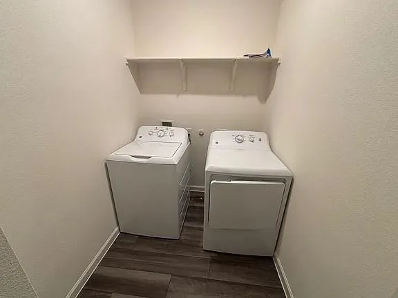 Laundry area featuring wood-finish flooring and a wall-mounted storage shelf