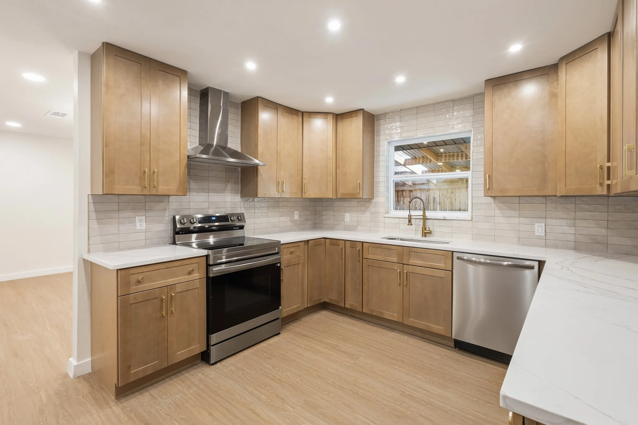 Kitchen featuring light wood-finish cabinetry, gold finish faucet, stainless steel appliances