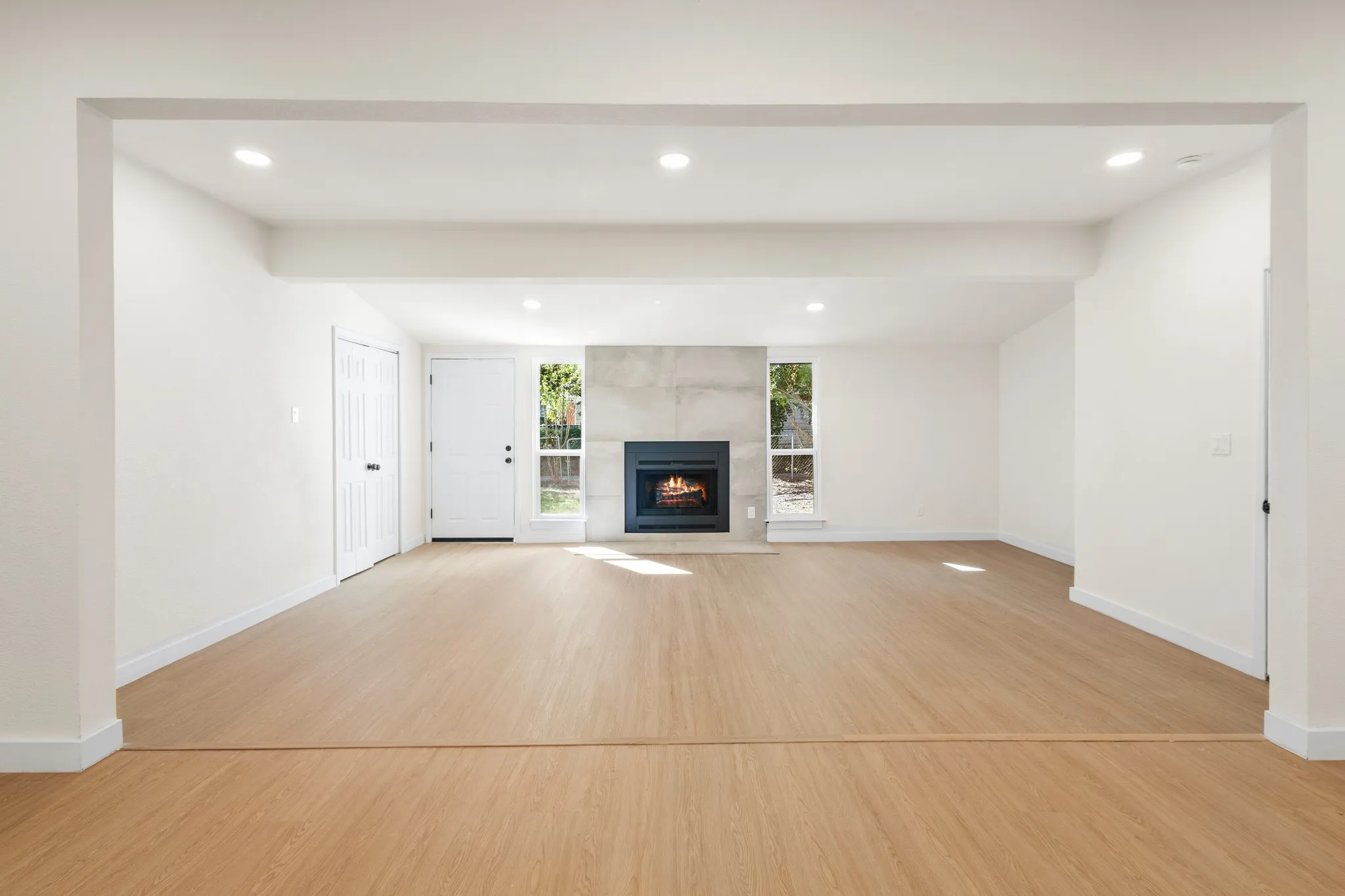 Open concept living room and family room featuring a built-in modern fireplace with a stone-finish surround
