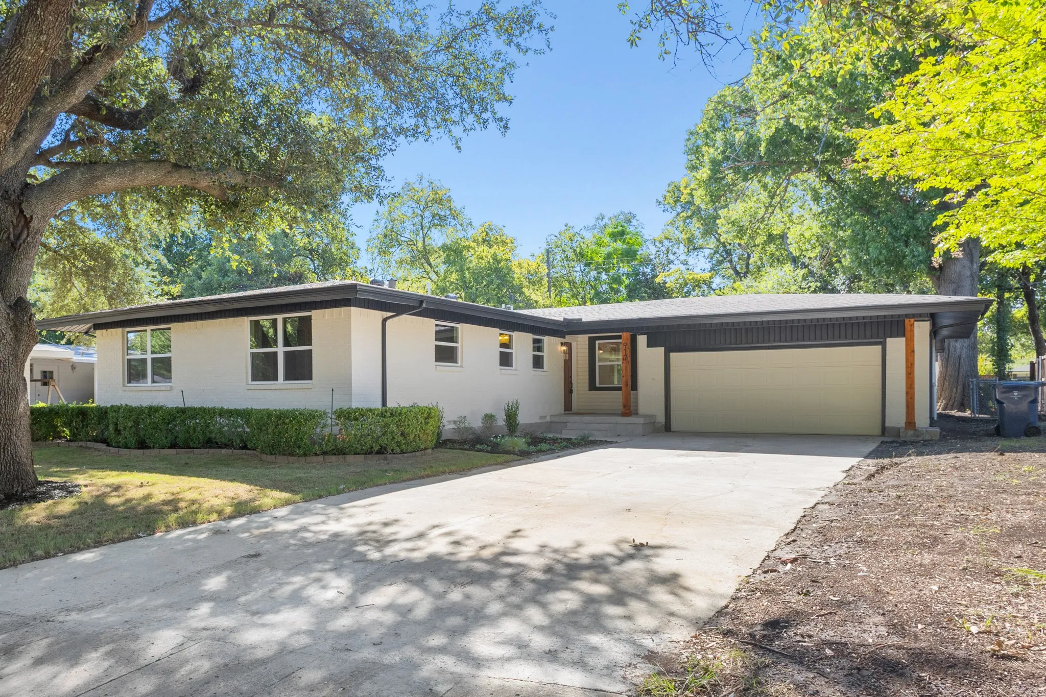 White exterior with black trim, long concrete driveway, attached two car garage