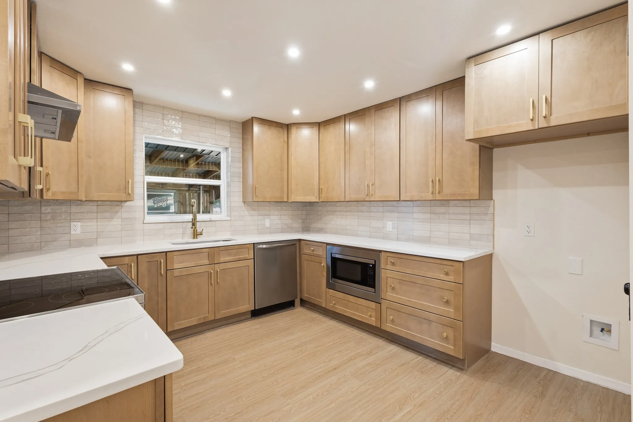 Kitchen featuring wood-finish cabinetry, Stainless steel dishwasher, built-in microwave, Designers Quartz countertops, and a subway tile backsplash