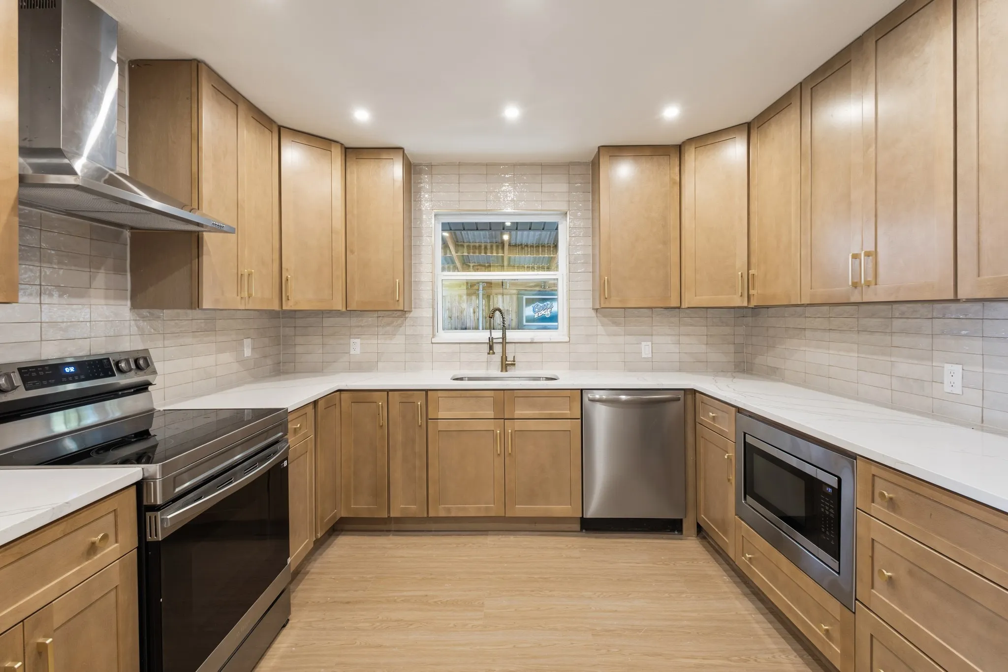 U-shaped kitchen featuring stainless steel Electric Range and powerful exhaust outside and a full-height tile backsplash
