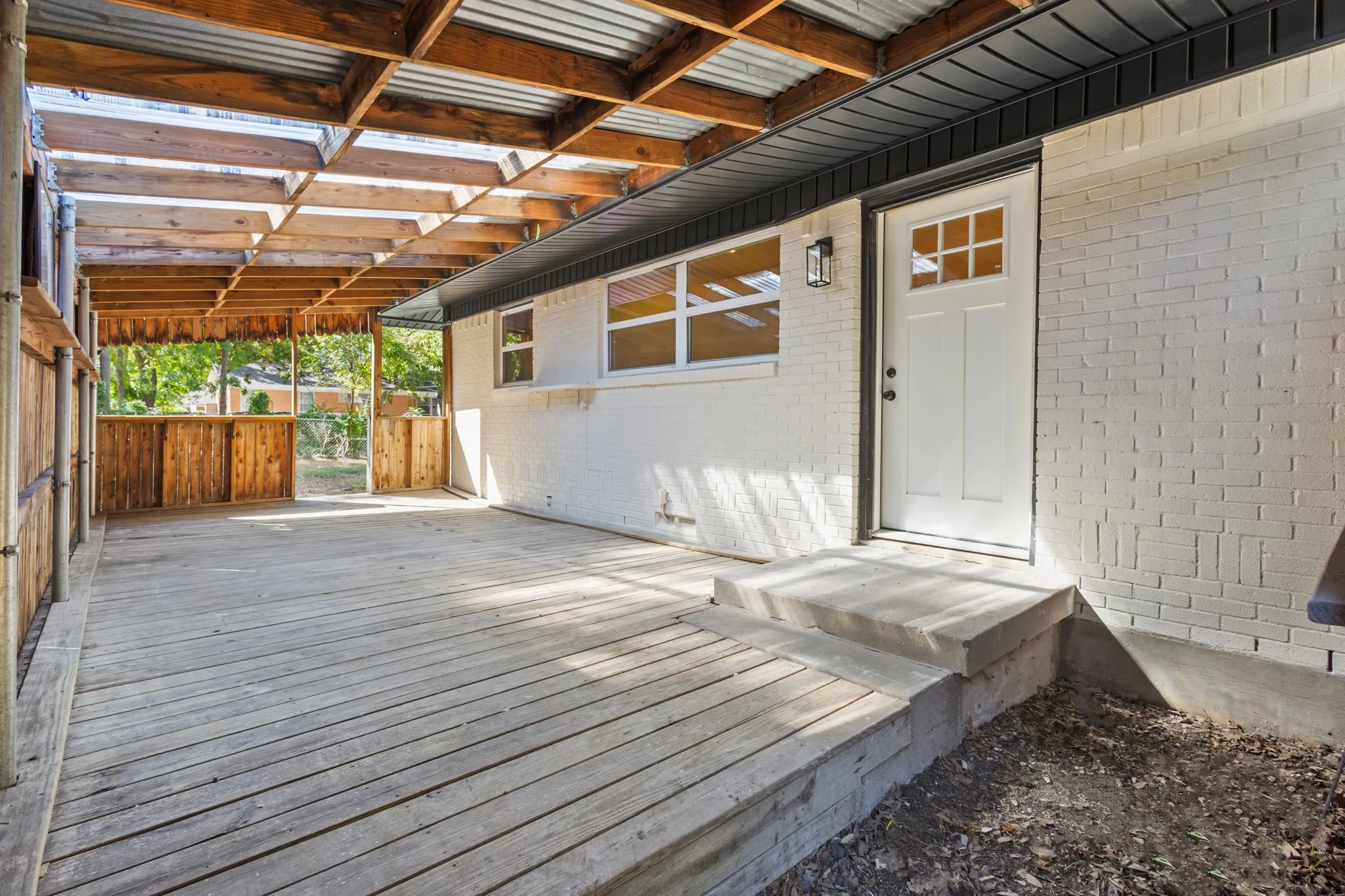 Expansive covered patio with exposed wood beams and a corrugated roof