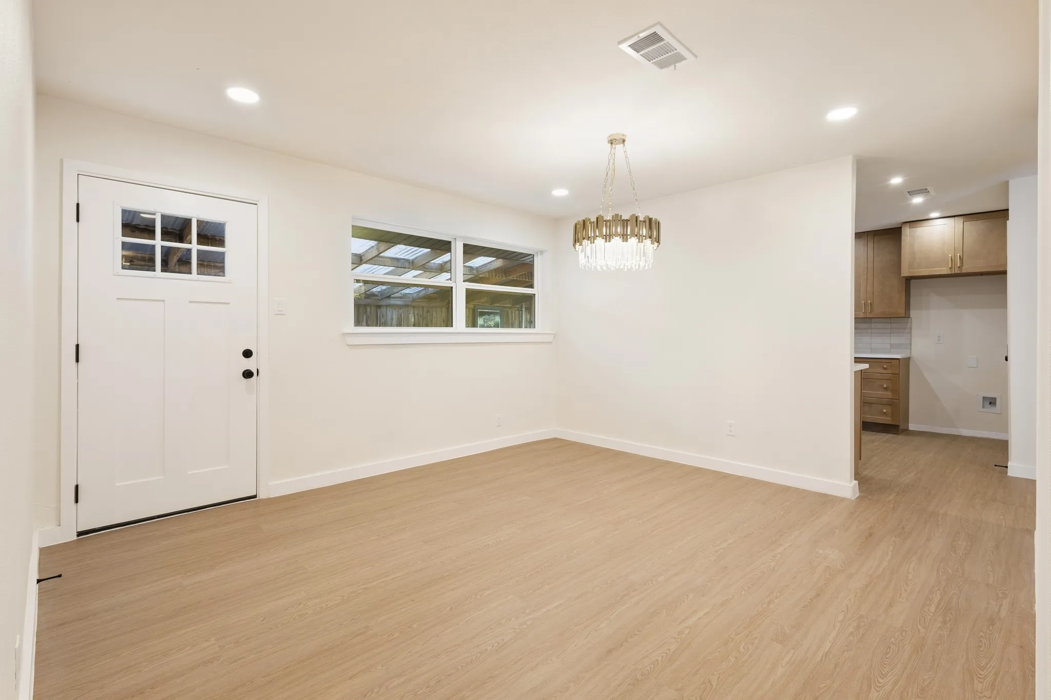 Dining room with can ceiling lighting, flush-panel door with window inserts, and a decorative chandelier