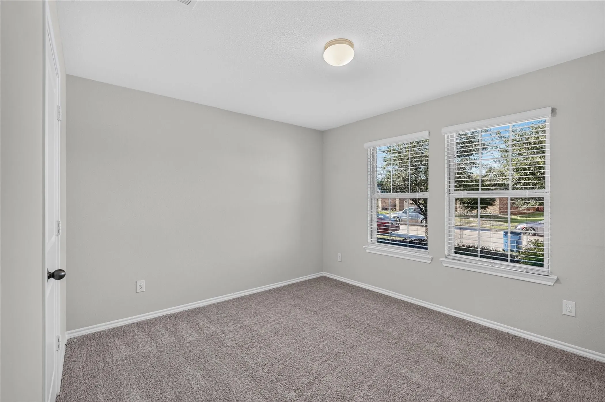 Neutral wall paint, gray carpet, and two double-hung windows with blinds