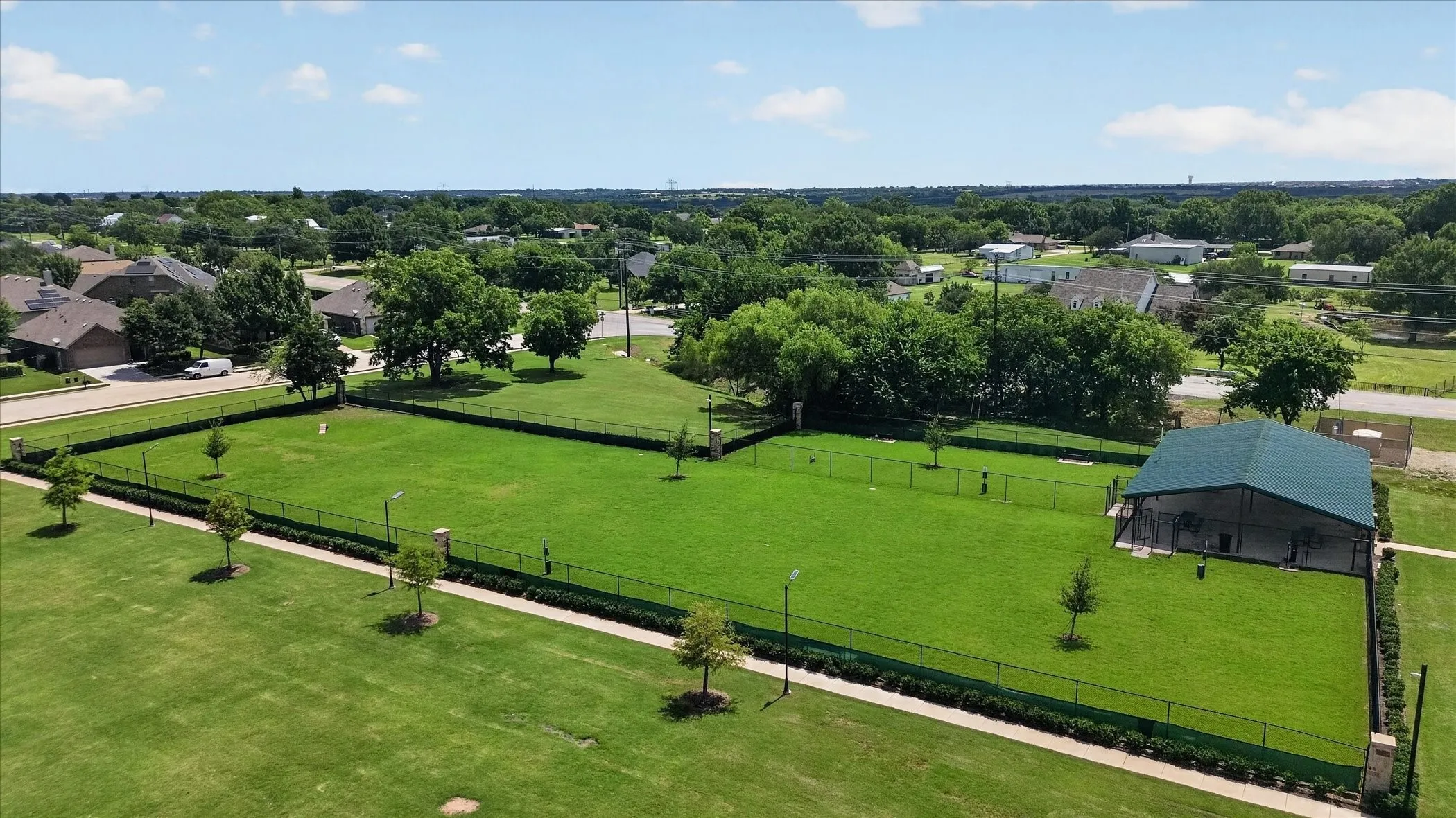 Expansive green spaces featuring a fenced-in area with a shelter structure