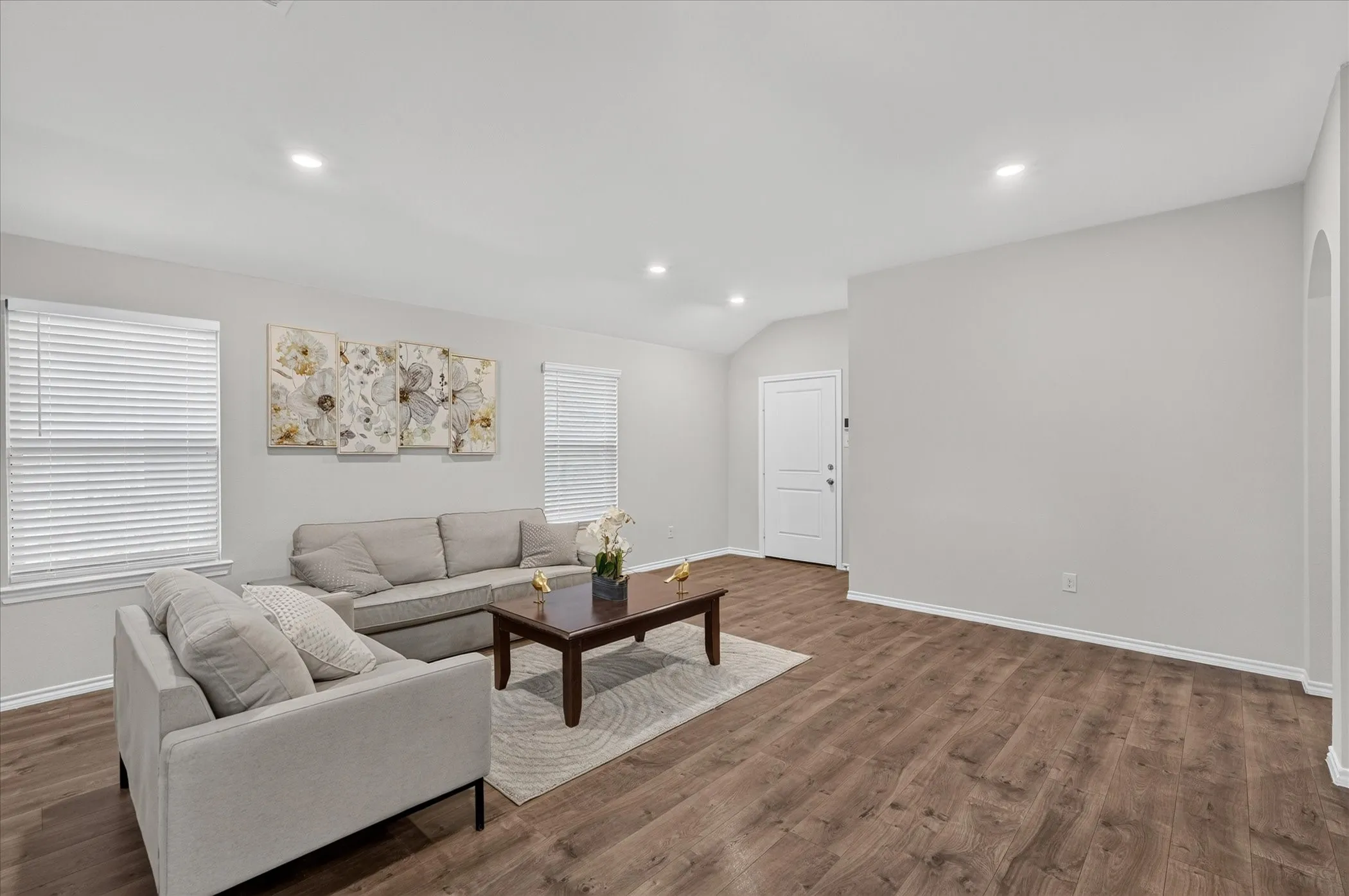 Spacious interior with wood-finish flooring, recessed lighting, arched entryway, and white paneled interior doors
