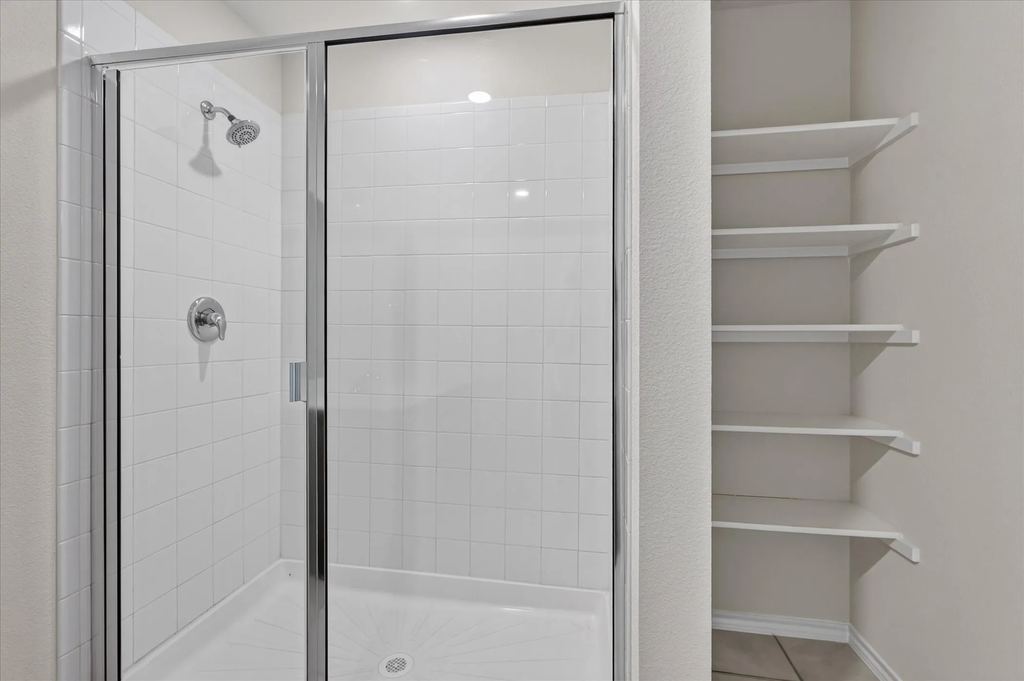 Modern primary bathroom featuring a frameless glass shower enclosure with chrome fixtures, white subway tile surround, and integrated shower lighting