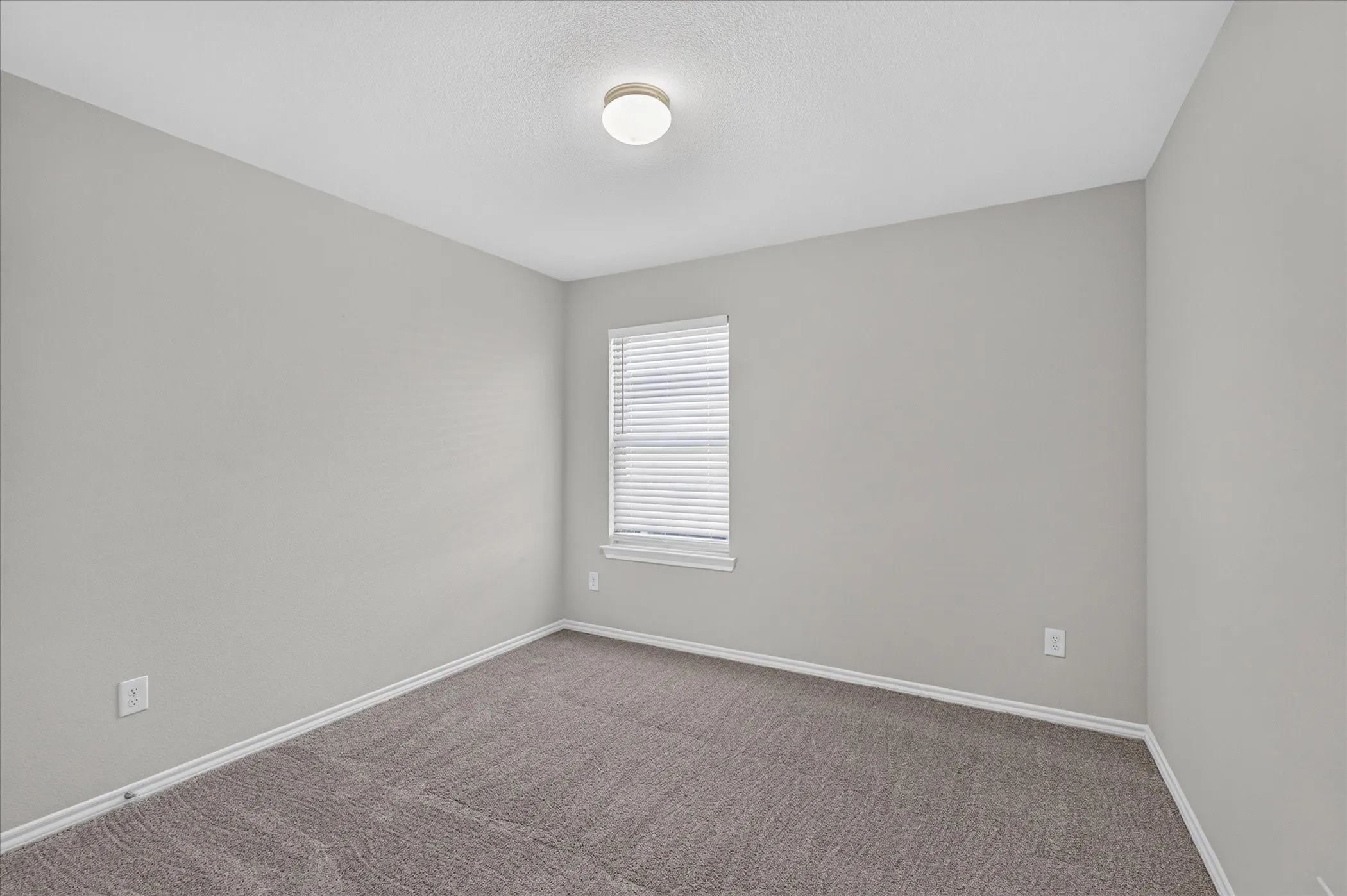 Bright secondary bedroom featuring neutral wall finishes, carpet flooring, a generous window with plantation shutters providing natural light, and recessed ceiling lighting