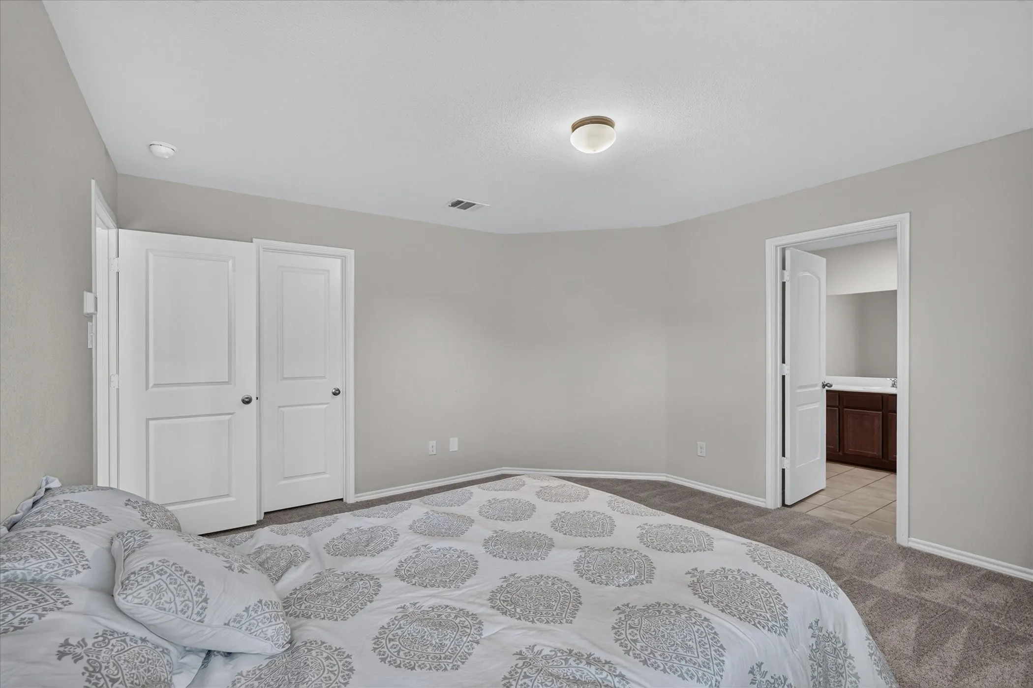 Wall-to-wall carpeting, light neutral wall paint, overhead flush-mount lighting, and bi-fold closet doors