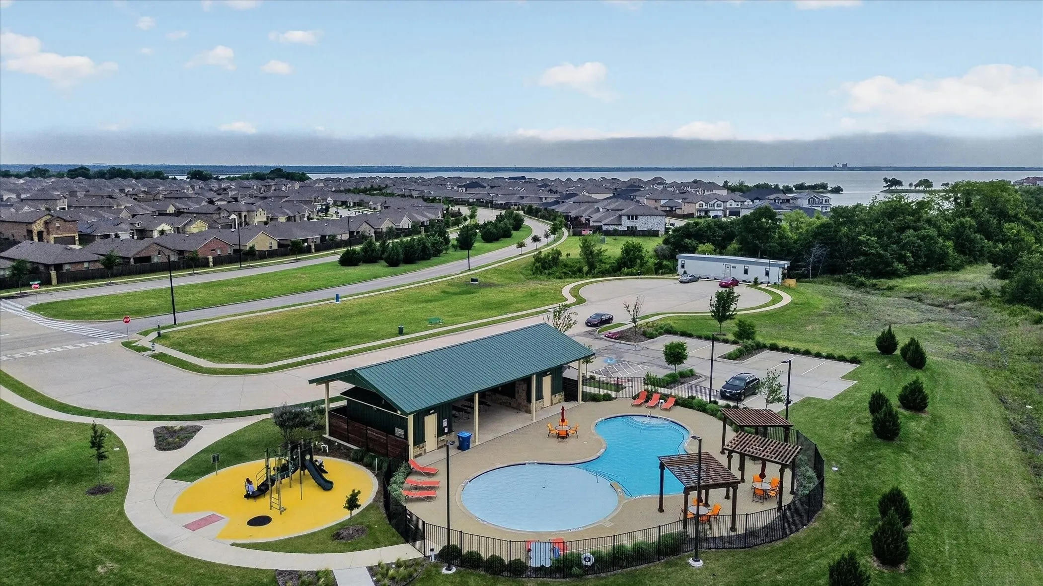 Expansive residential community featuring a resort-style amenity center with a custom saltwater pool, splash pad with water features, and dedicated play structure set within manicured landscaping