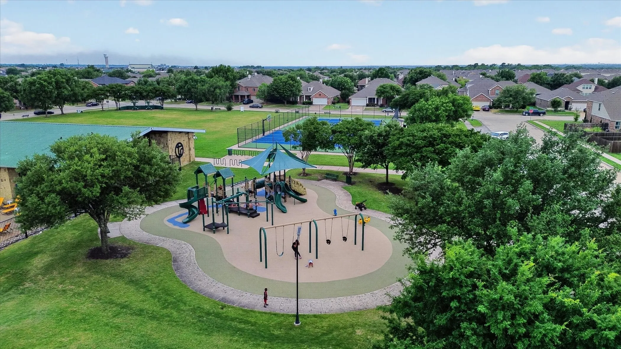 Community park with a playground, open green space, tennis courts, and a covered pavilion