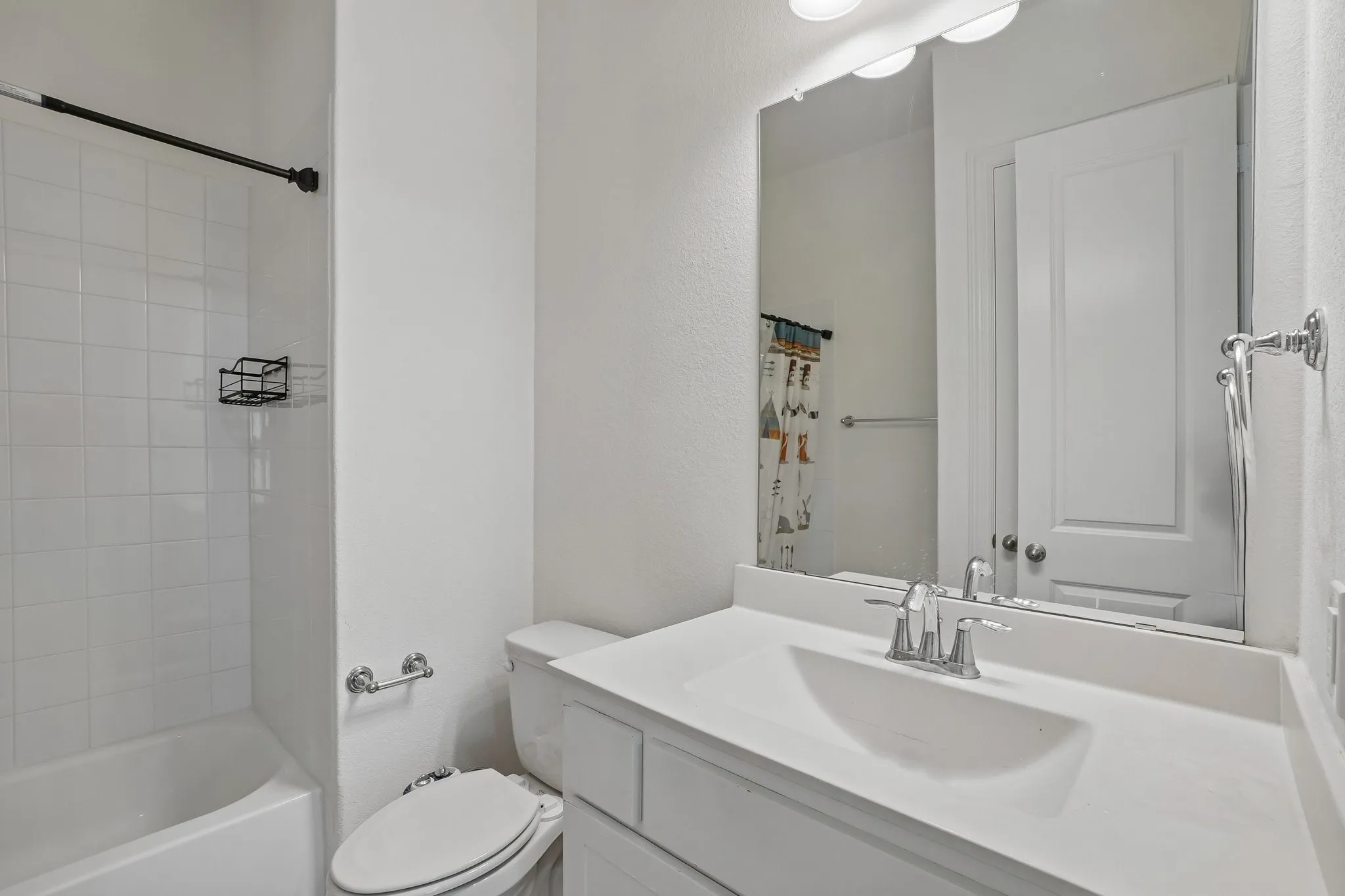 Bathroom featuring a tub/shower combination, white tile surround, single vanity with integrated sink, and chrome fixtures