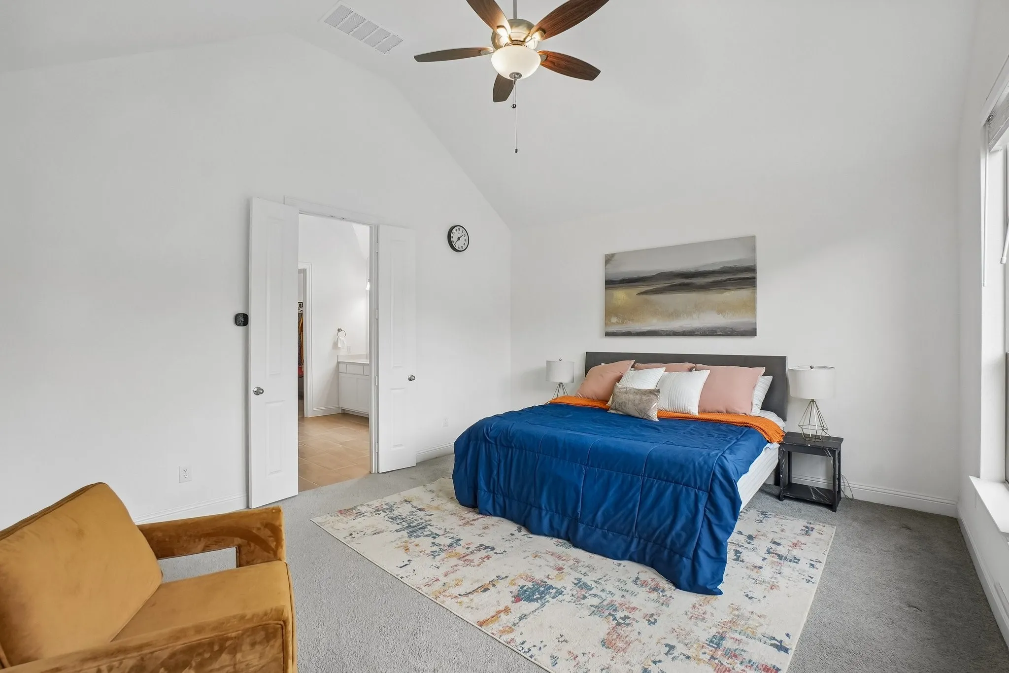 Vaulted ceiling with a ceiling fan, light gray carpet flooring, white walls, and a large window