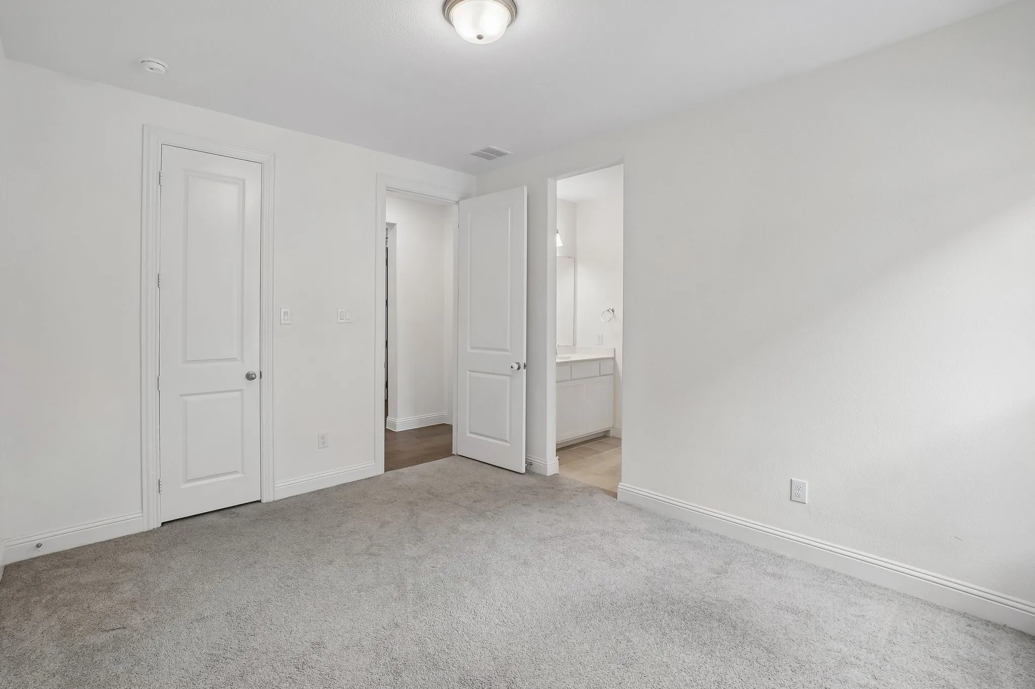 Neutral-toned carpet flooring, white walls, and bright overhead lighting