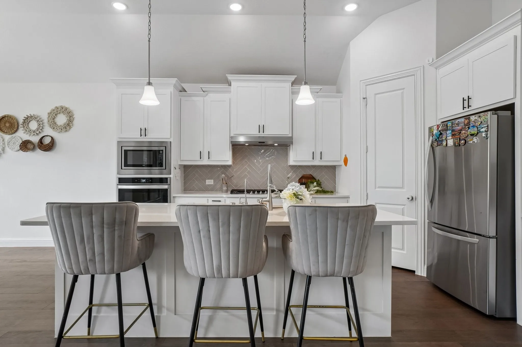 White cabinetry with crown molding, stainless steel appliances, herringbone tile backsplash, kitchen island with seating, and dark wood-finish flooring