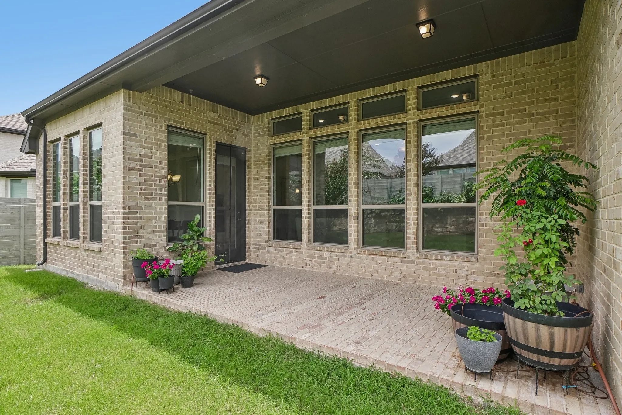 Covered patio featuring brick construction, a screened door, and multiple windows