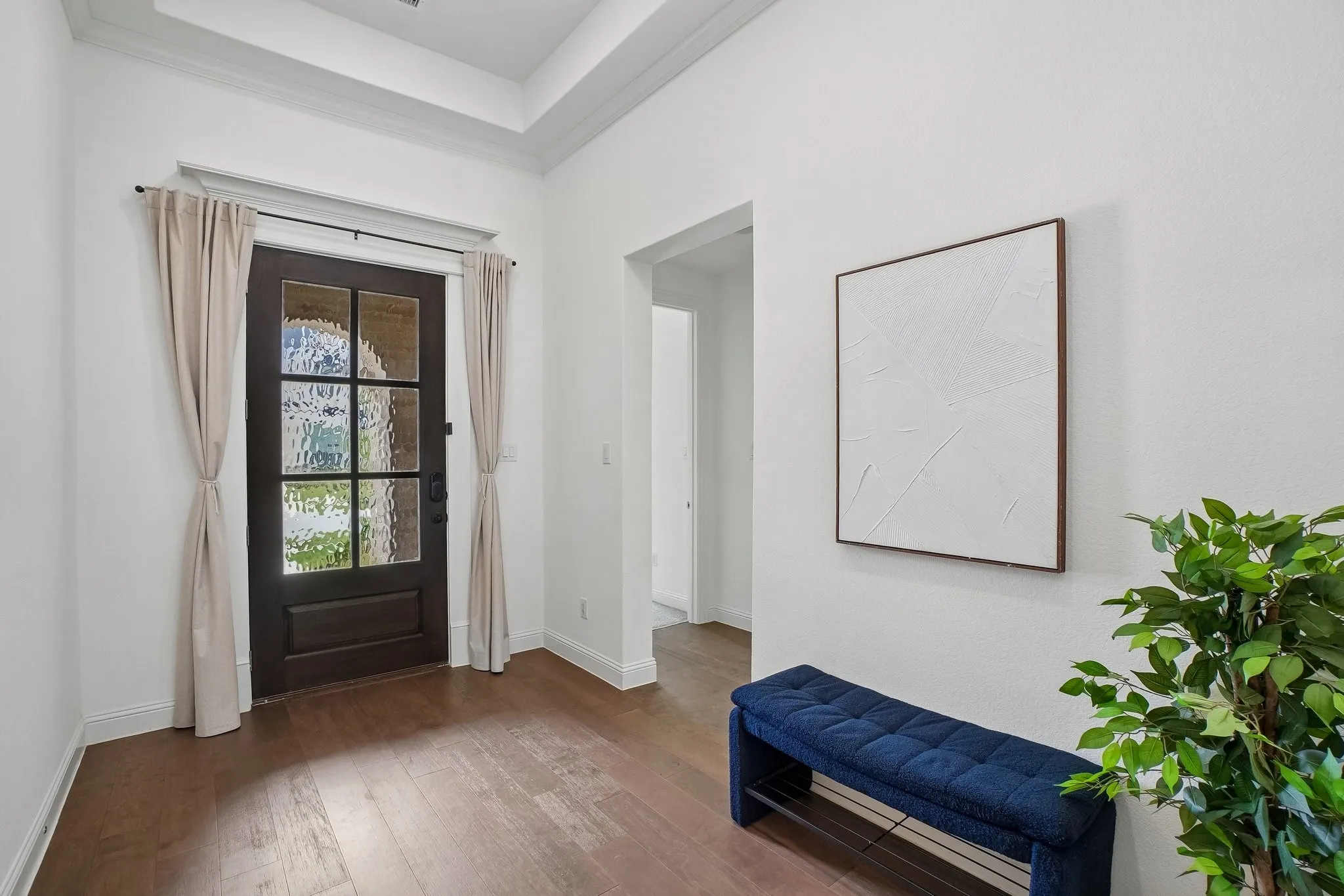 Dark wood-finish entry door with multiple glass panes, wood-finish flooring, and crown molding