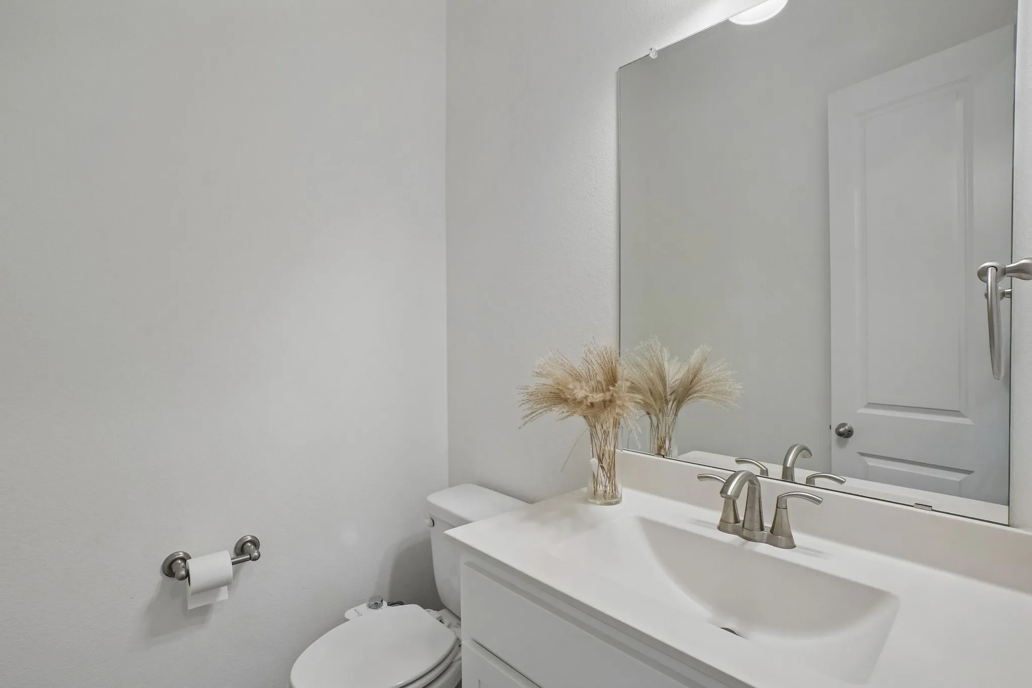 Vanity with an integrated sink, brushed nickel faucet, mirror, and overhead lighting