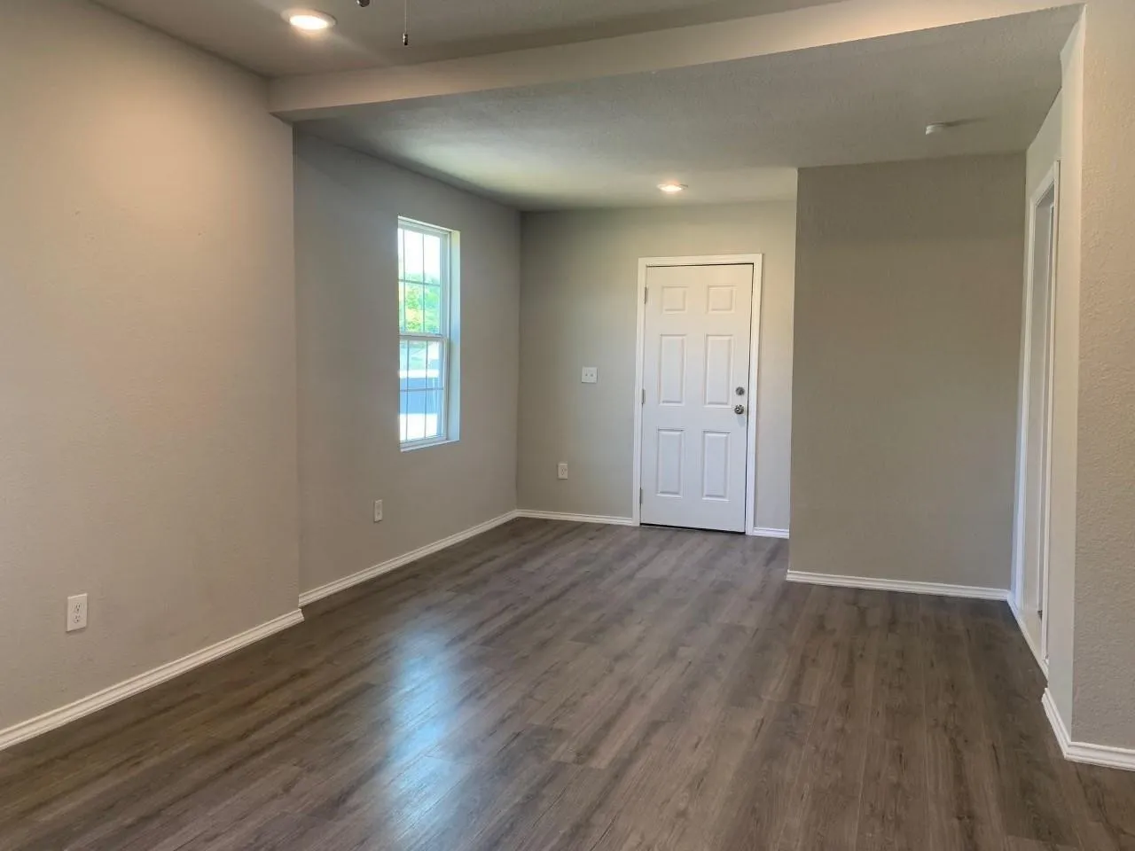Wood-finish flooring, recessed lighting, and a white paneled door