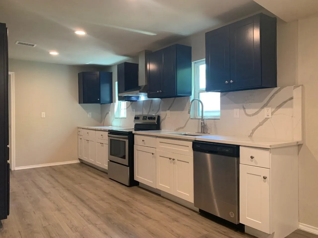 Kitchen featuring two-tone cabinetry, wood-finish flooring, recessed lighting, and stainless-steel appliances